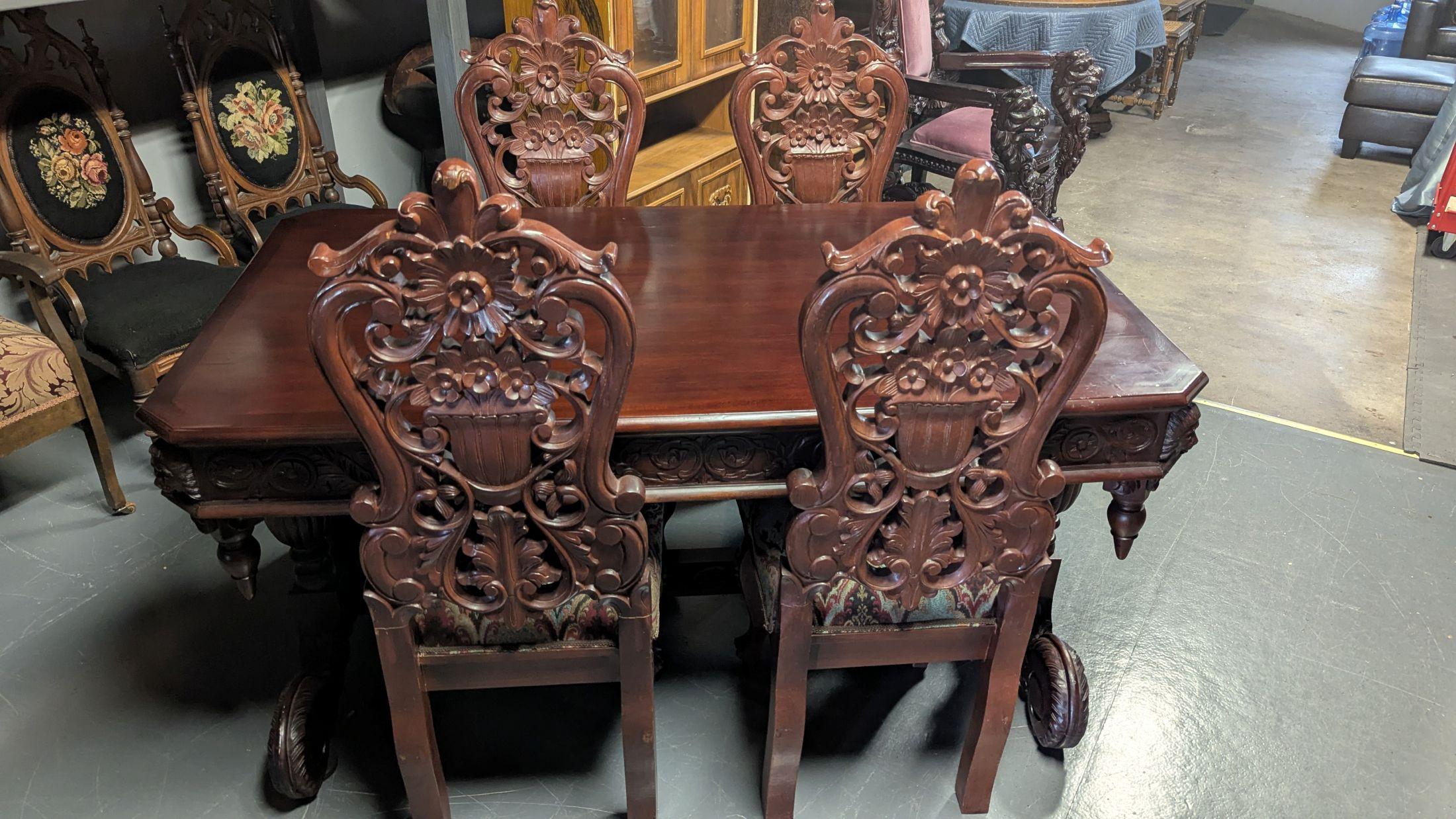 Beautifully carved tressel table with four highly carved chairs, upholstered in colorful Moroccan pattern.  The table 63x35x31 has carved wide skirt with lion heads on the corners, each side tressel leg has two bulbous columns above large scrolled