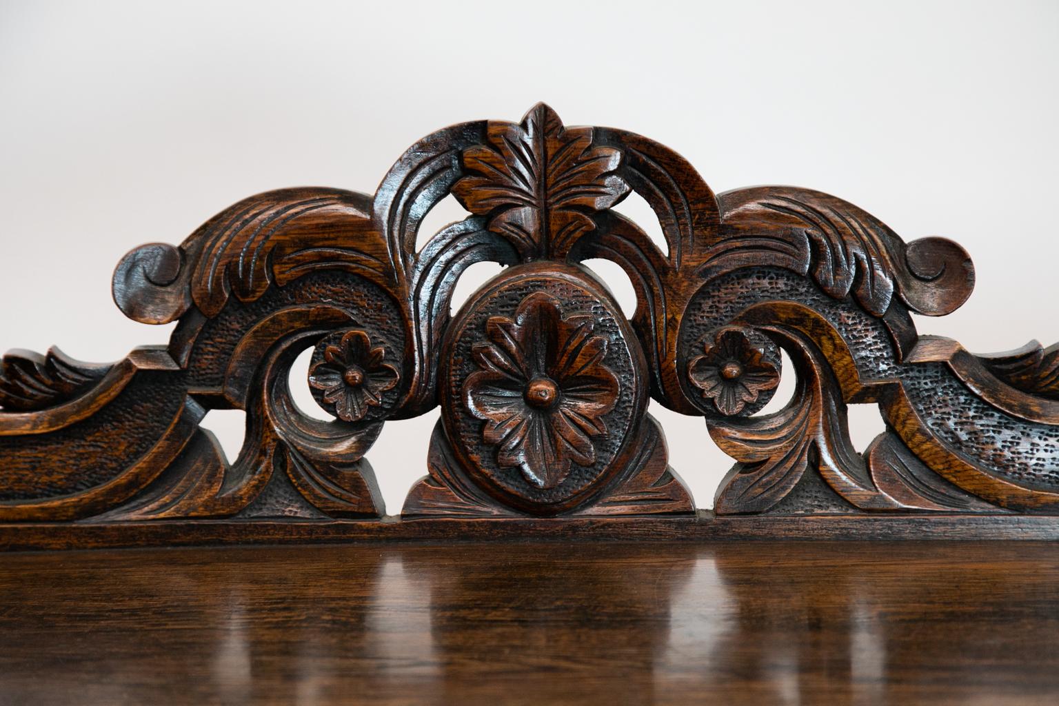 Carved two-tier English shelf cupboard, the crest and sides of the top are carved with floral arabesques and have fluted mushroom finials. The shelf edges are carved and stipled. The doors have carved baskets of fruit that are carved in very high