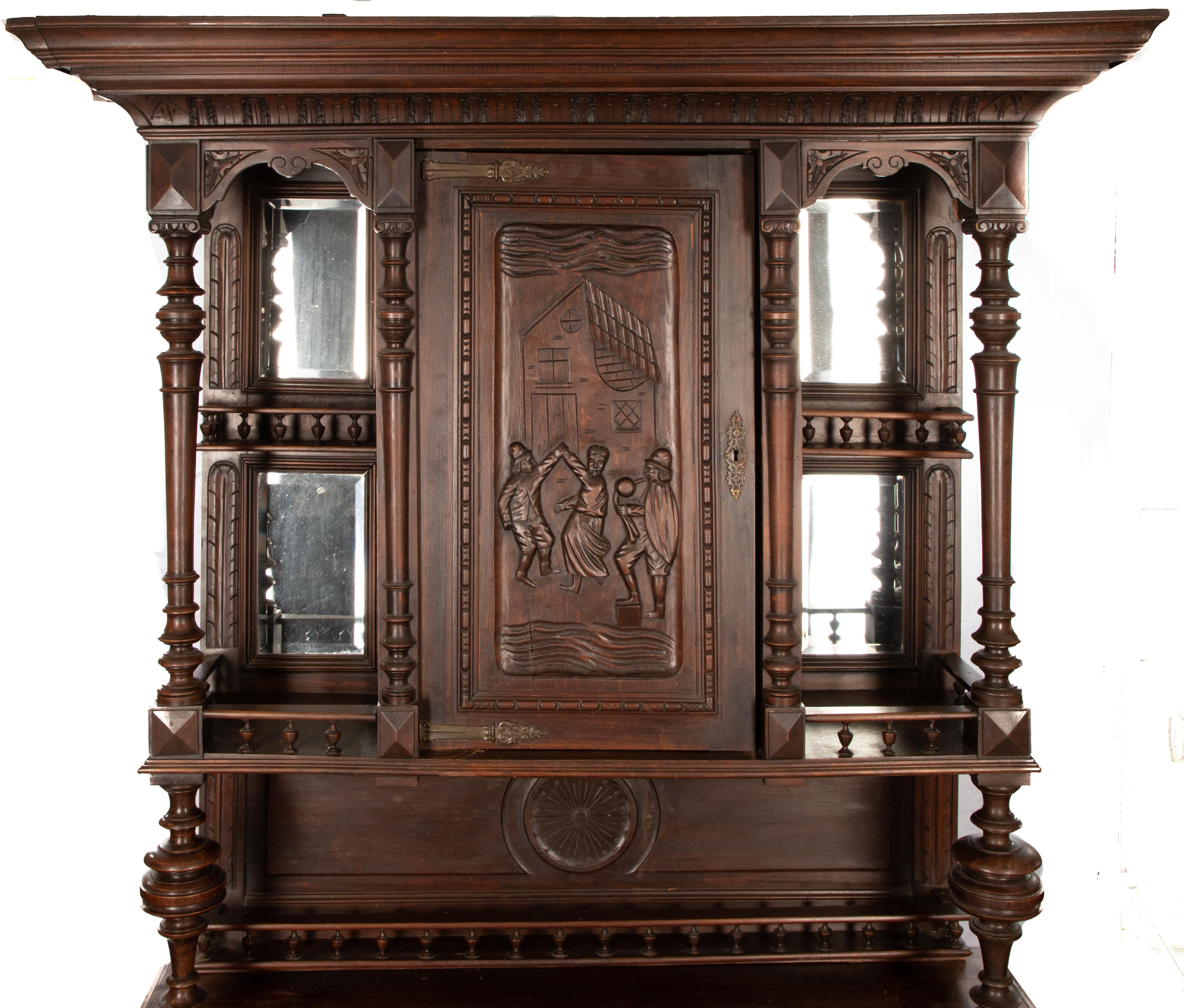 Offering this gorgeous carved walnut Belgium server. Starting on a stately base with two heavily carved doors. The top has a single door in the center and on either side has open shelves backed with mirrors.
