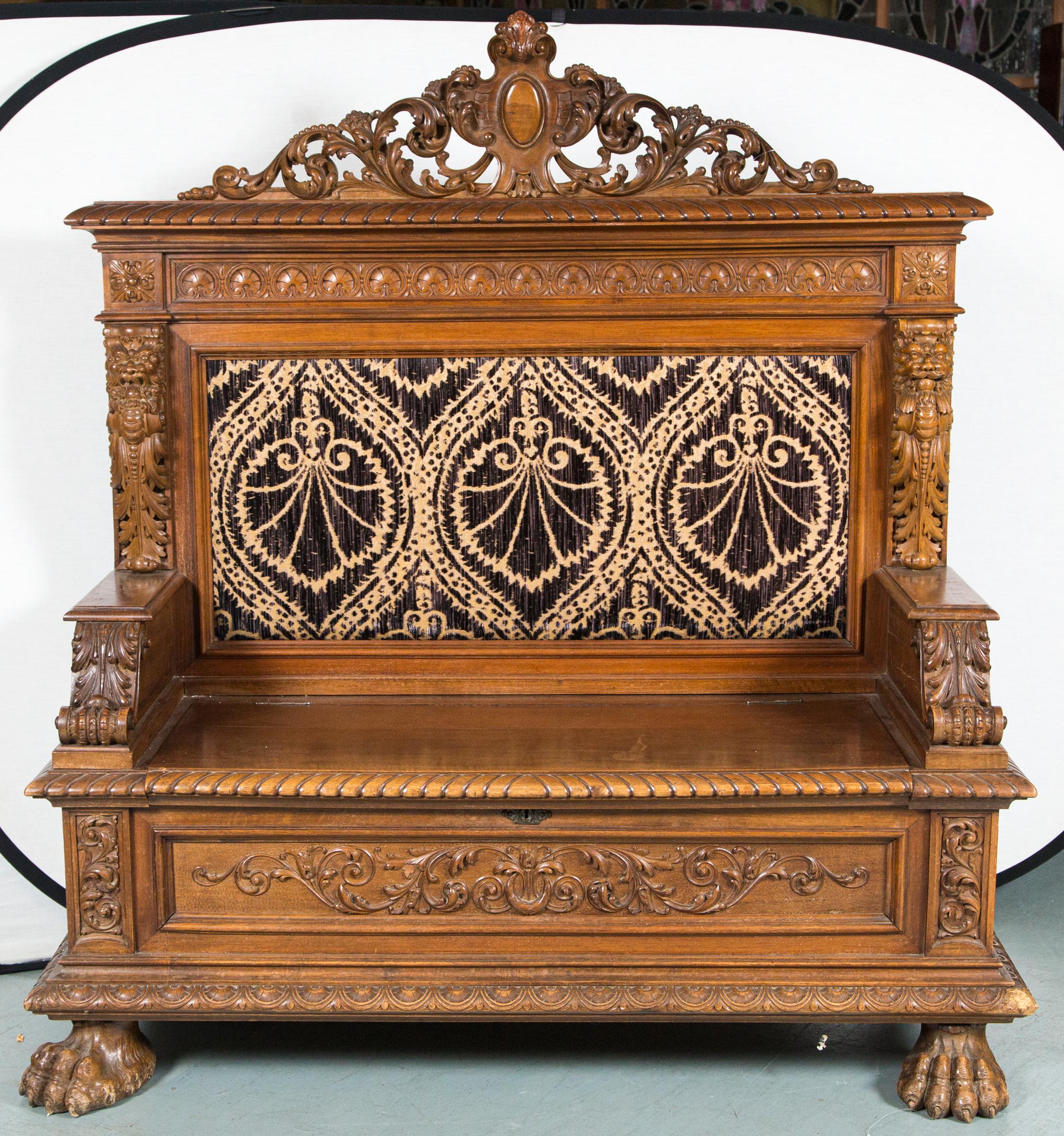 Beautiful walnut carved 19th century bench. Wonderful pierced-carved crest at the top. Carved lions and acanthus leaf designs to each side. Seat lifts for storage. Carved lion paw feet that show some wear. Upholstery shows some wear. Great 19th