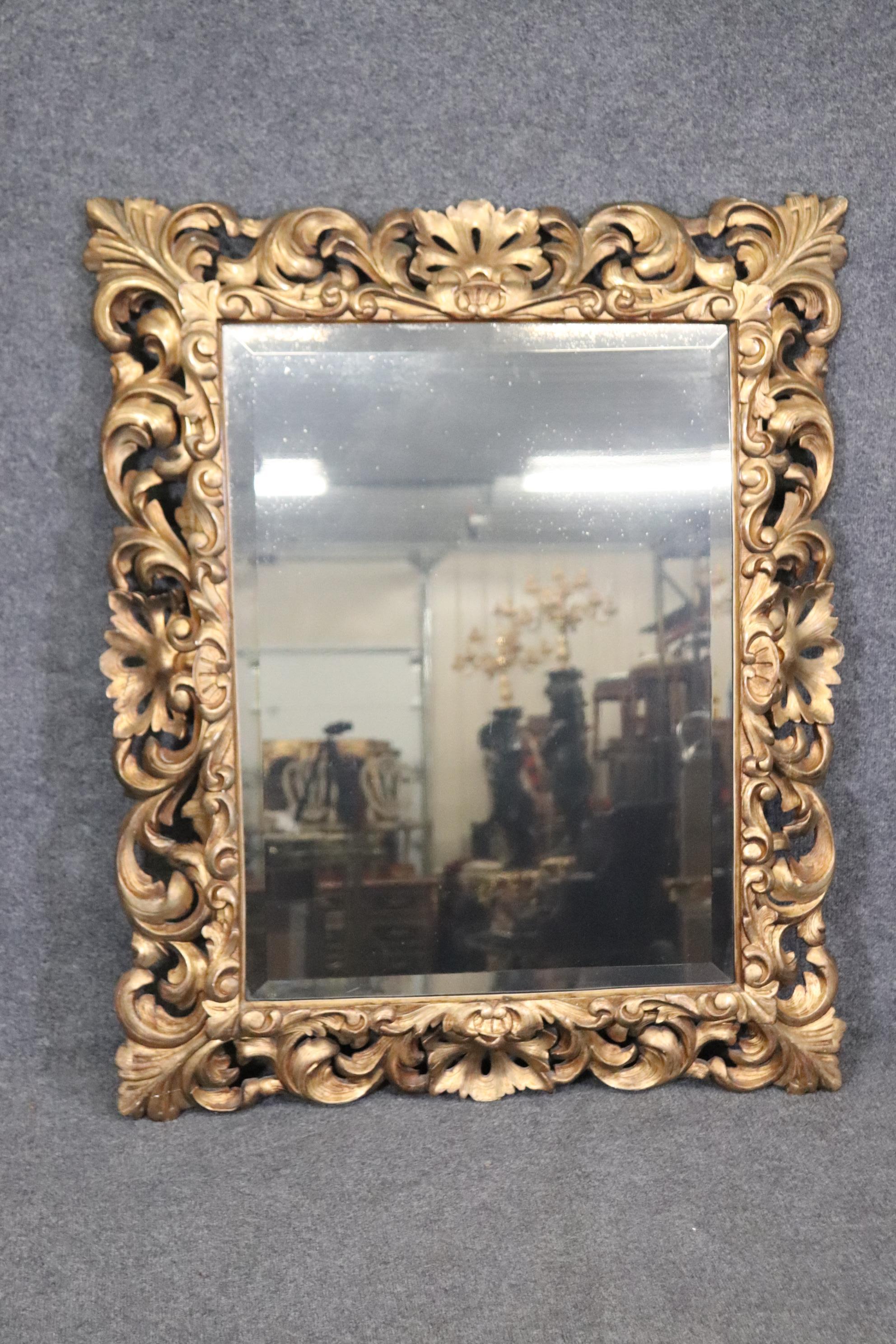 This is a beautiful intricately carved mirror with a gorgeous gilded frame and beveled glass mirror. Measures 45.75 tall x 38 wide x 3.75 deep and dates to the 1940s era. Has old minor repairs to the back, and minor signs of wear and age from use.