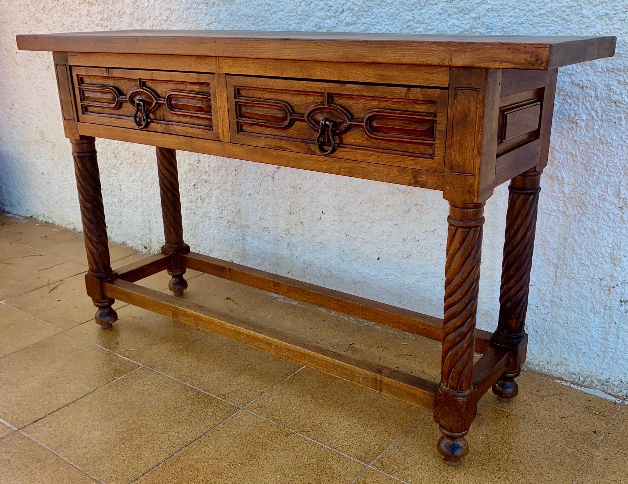 Spanish Renaissance Revival console table crafted in solid wood, dating from the early 20th century. The front features two drawers with elegant geometric carved panels and original metal ring pulls, expressing the bold decorative language of