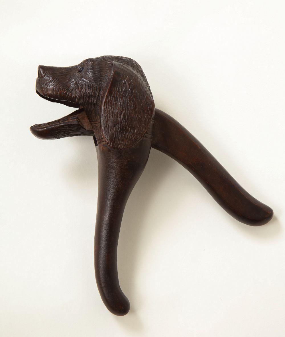 The finely carved hound's head with glass eyes, with mouth opening to receive nuts.