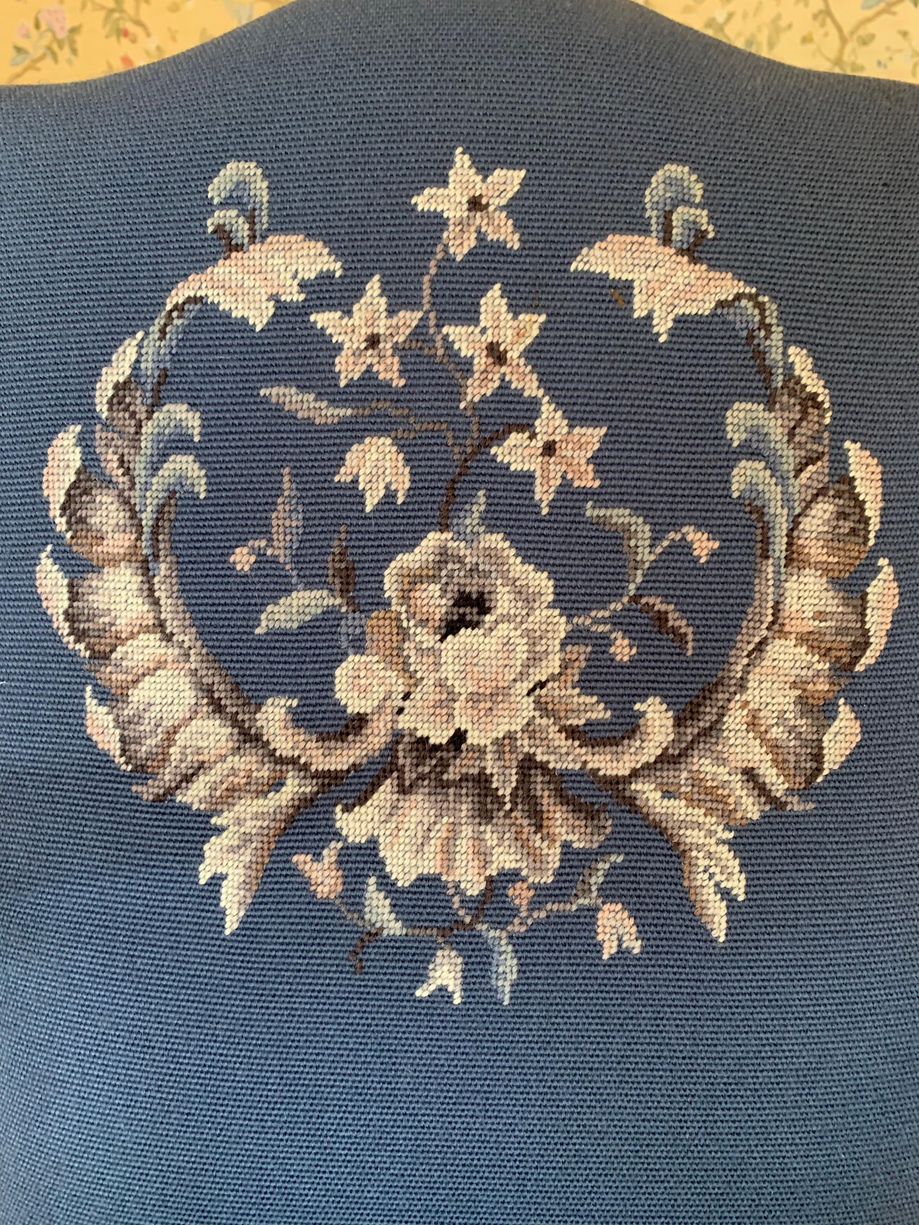 A magnificent set of four embroidered needlepoint dining chairs that have a very regal emblem at backrest. The emblem makes one think these chair belong in the White House yet they come from a grand home in Connecticut. One arm has a crack that has