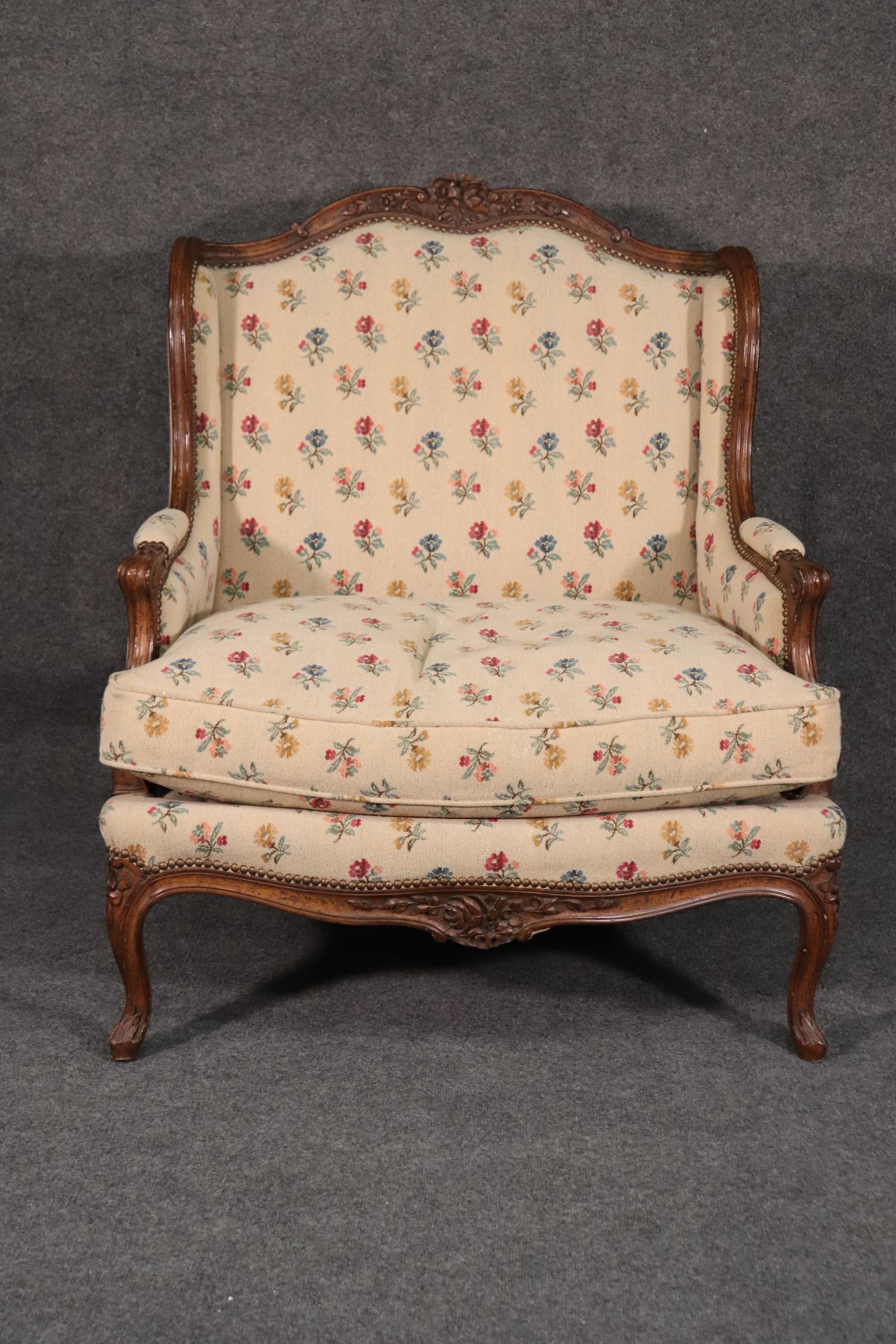 This is a gorgeous and beautifully carved bergere or marquis as it is a wide chair. The chair has terrifi carving and even the upholstery is beautiful and tasteful. The chair dates to the 1950s era and is in good original condition. Measures 42 tall