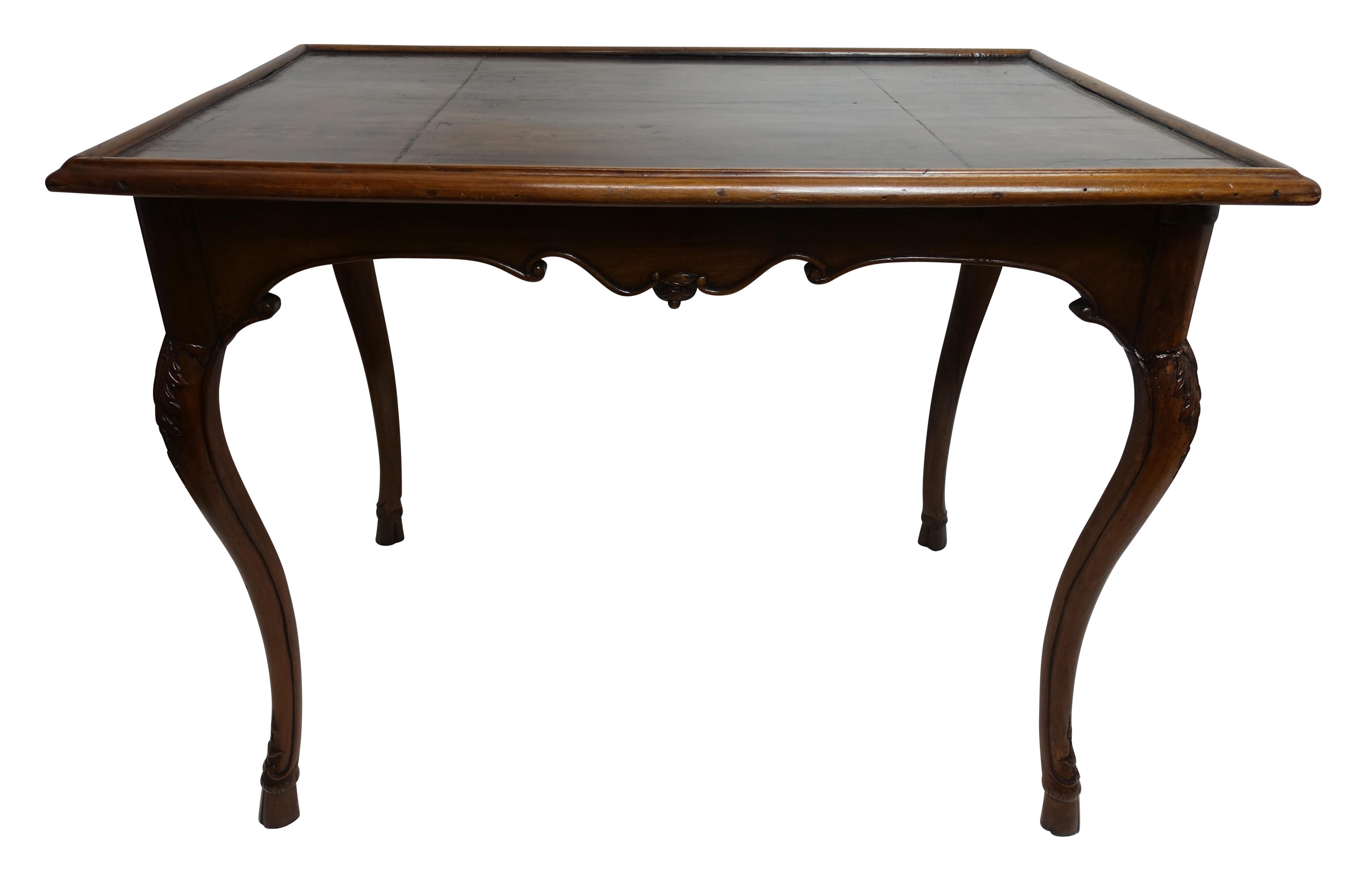 Beautifully carved walnut game table with inset leather top. Having a shapely apron, sitting on cabriole legs with carving at knees and ending with cloven hoof detail. The swing out cup or candle holders were most likely added in the mid-20th