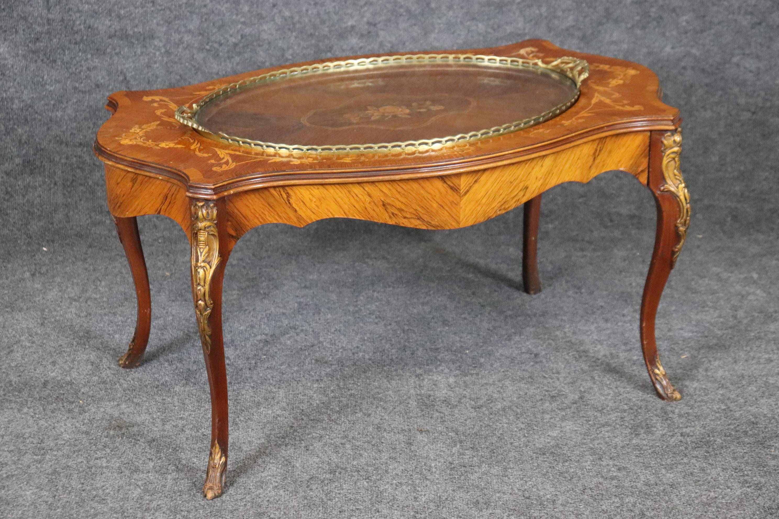 This is a fine quality walnut, bras and glass serving tray top coffee table. The tray is entirely removable for serving drinks or a dush of hummus with vegetable crackers. The table is from the 1950s era and will show old repairs and damages. These