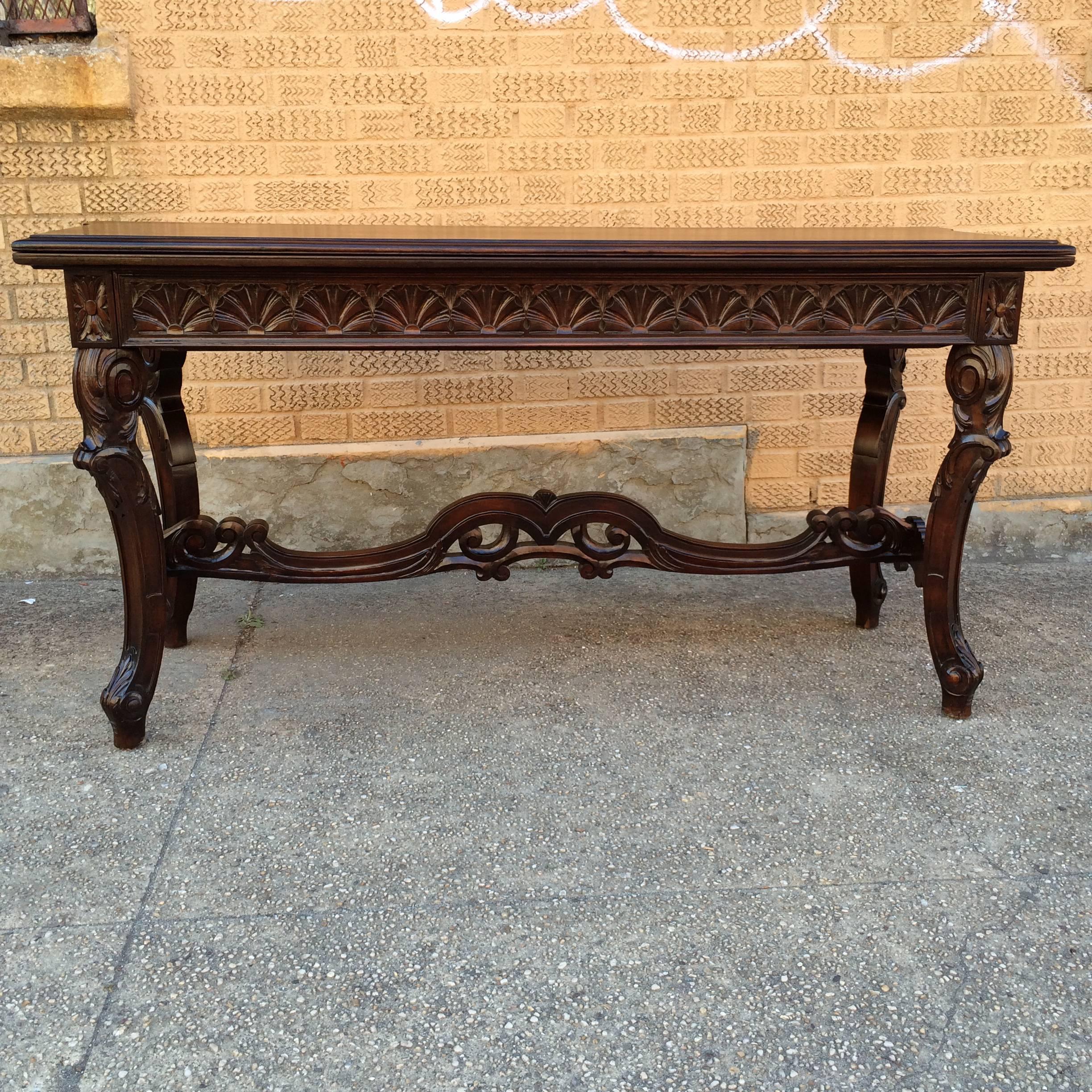 Jacobean, walnut refectory console table circa 1920s features an intricately carved base with a stacked leaf that opens into a 62