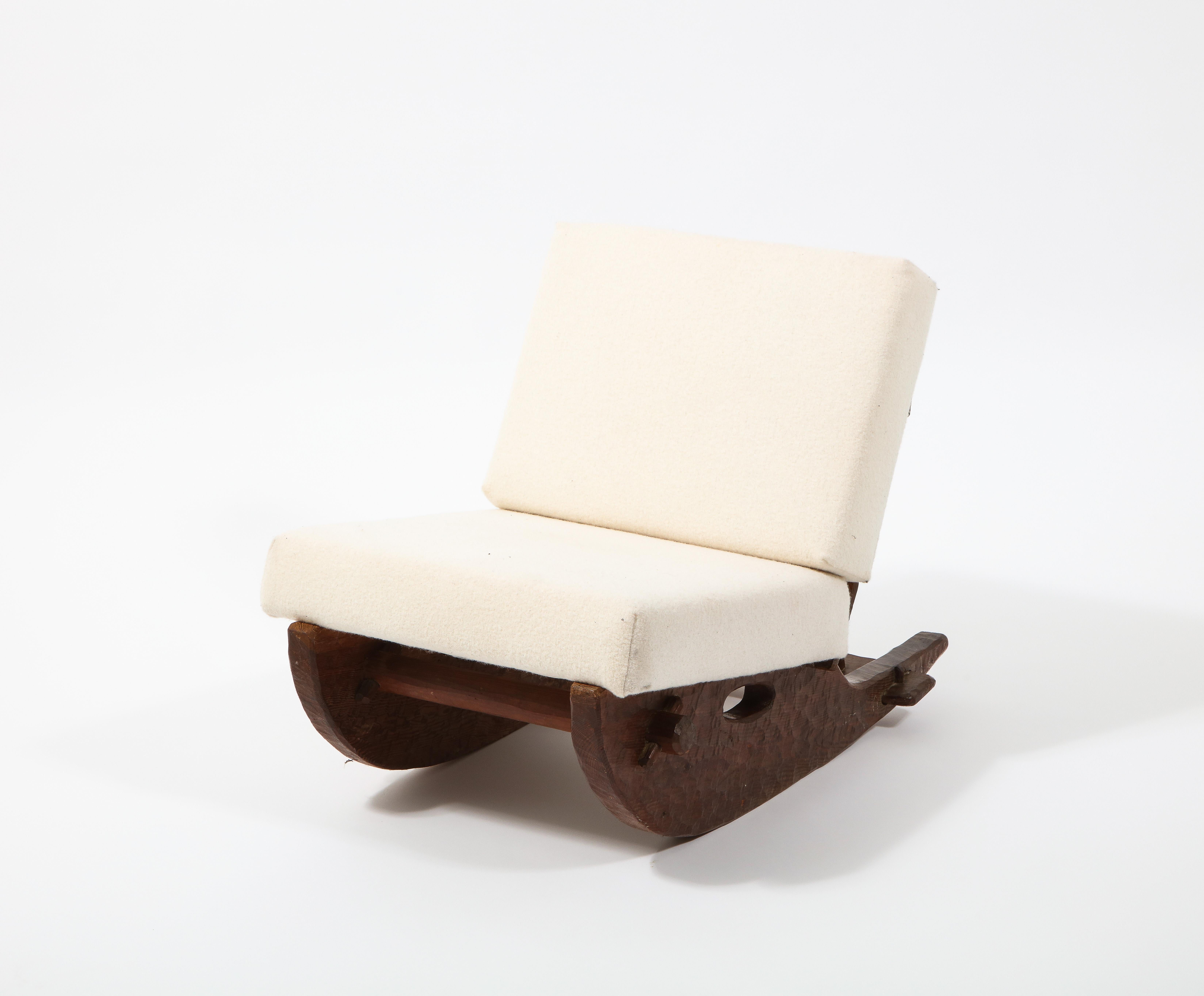 Low rocking chair attributed to Jean Touret. The solid oak base is carved and hand gouged in a brutalist fashion; butterflies and dowels hold its various components.