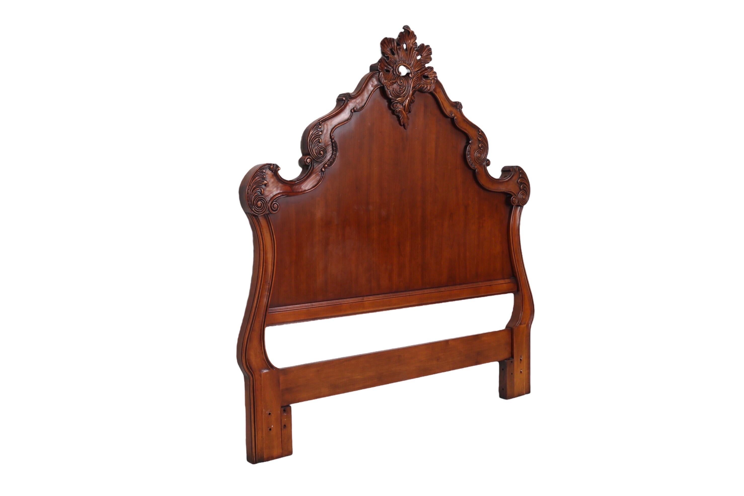 A Rococo style carved queen size headboard made of walnut. The thick undulating crest rail is beveled with a profusion of asymmetrical scrollwork and a large pierced rocaille ornamentation at the center.
 