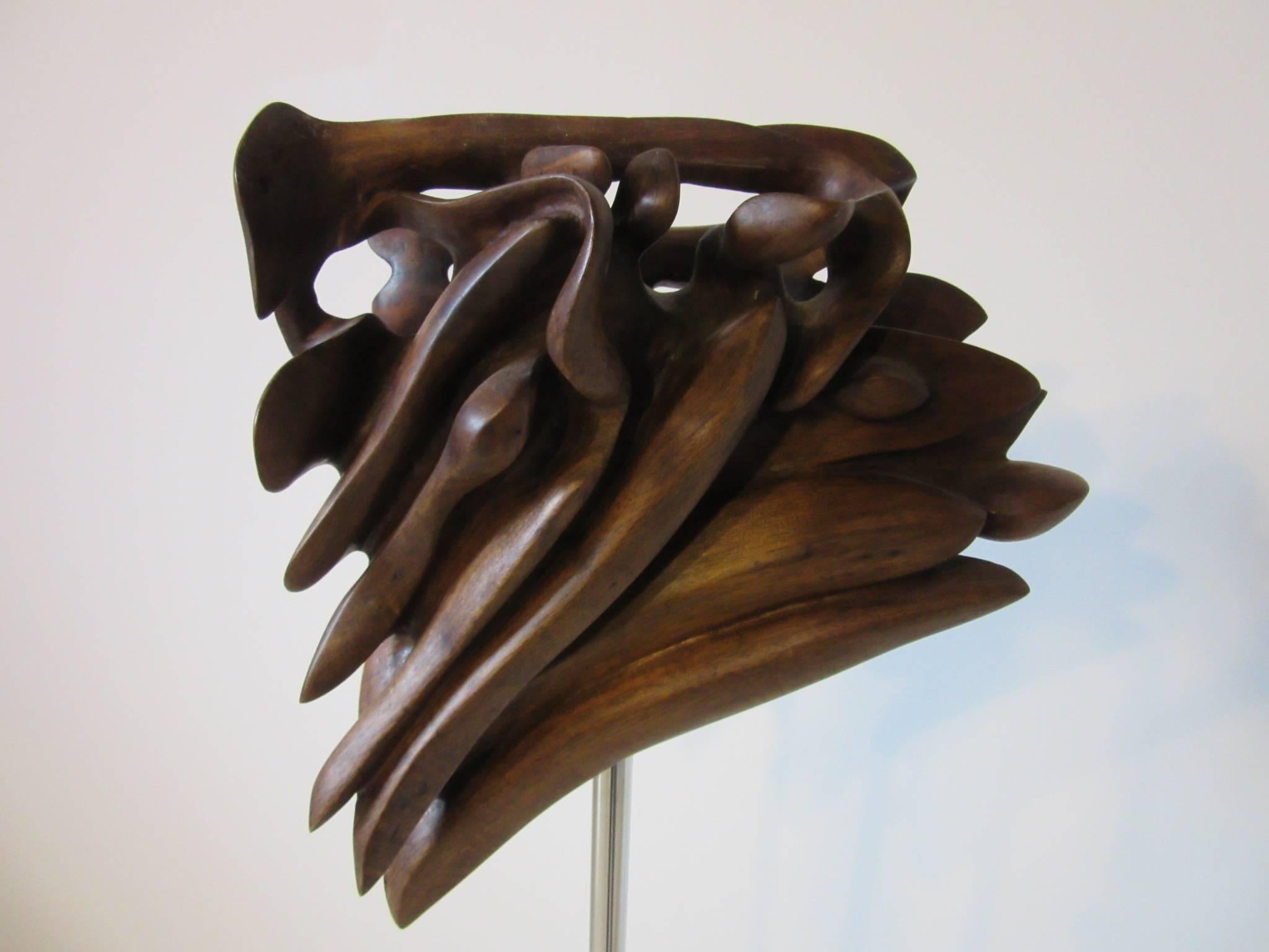 A carved walnut sculpture displayed on a chrome, black and white Lucite base mixing hard surfaces and the organic sculptural texture of the wood . Carved artist signature to the walnut 