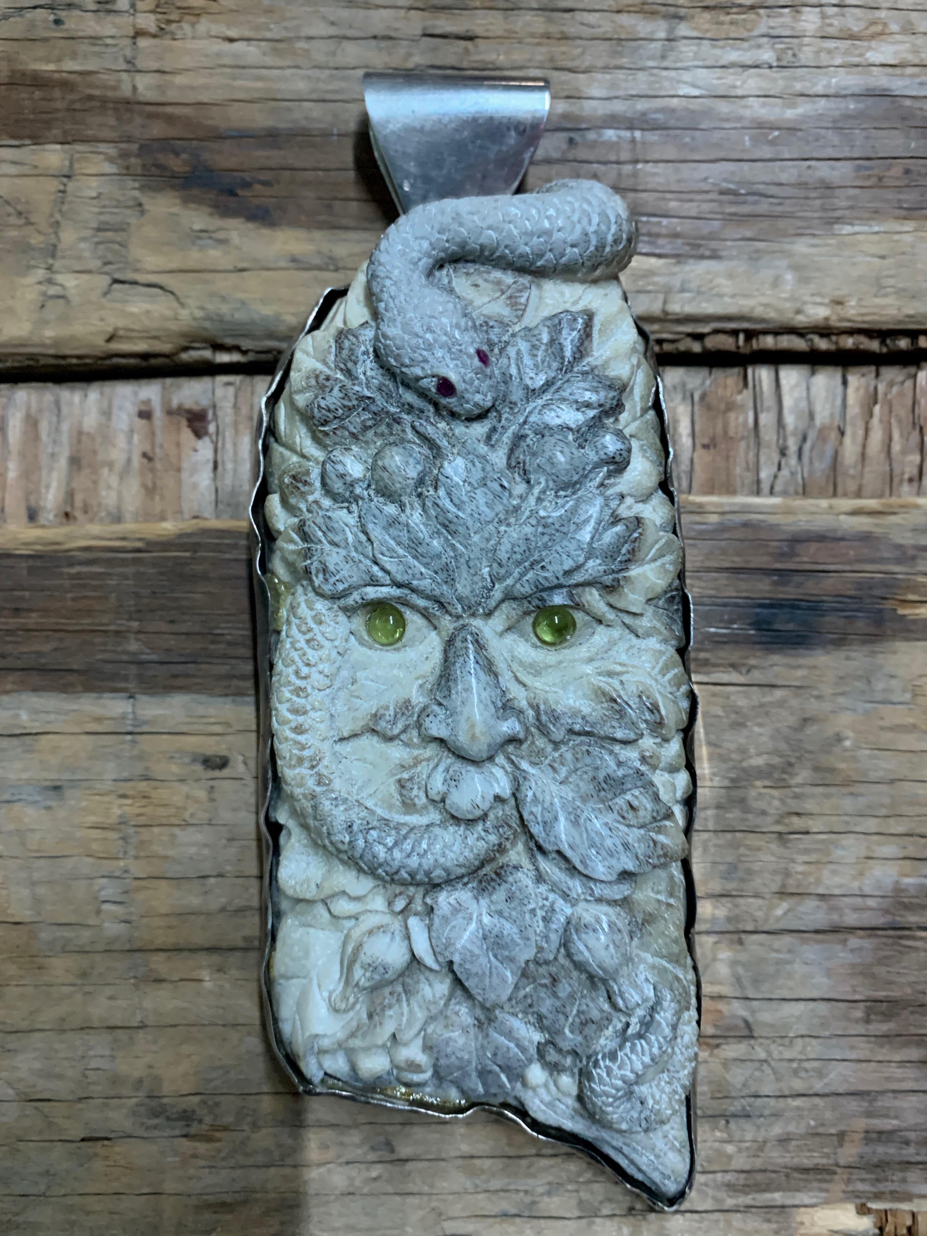 Intricate carving of a green-eyed man entwined with a snake. The snake eyes are rubies. The back of the piece feature carvings of leaves, representational of the fall harvest. 

The Green man is believed to symbolize the cycle of life, death and