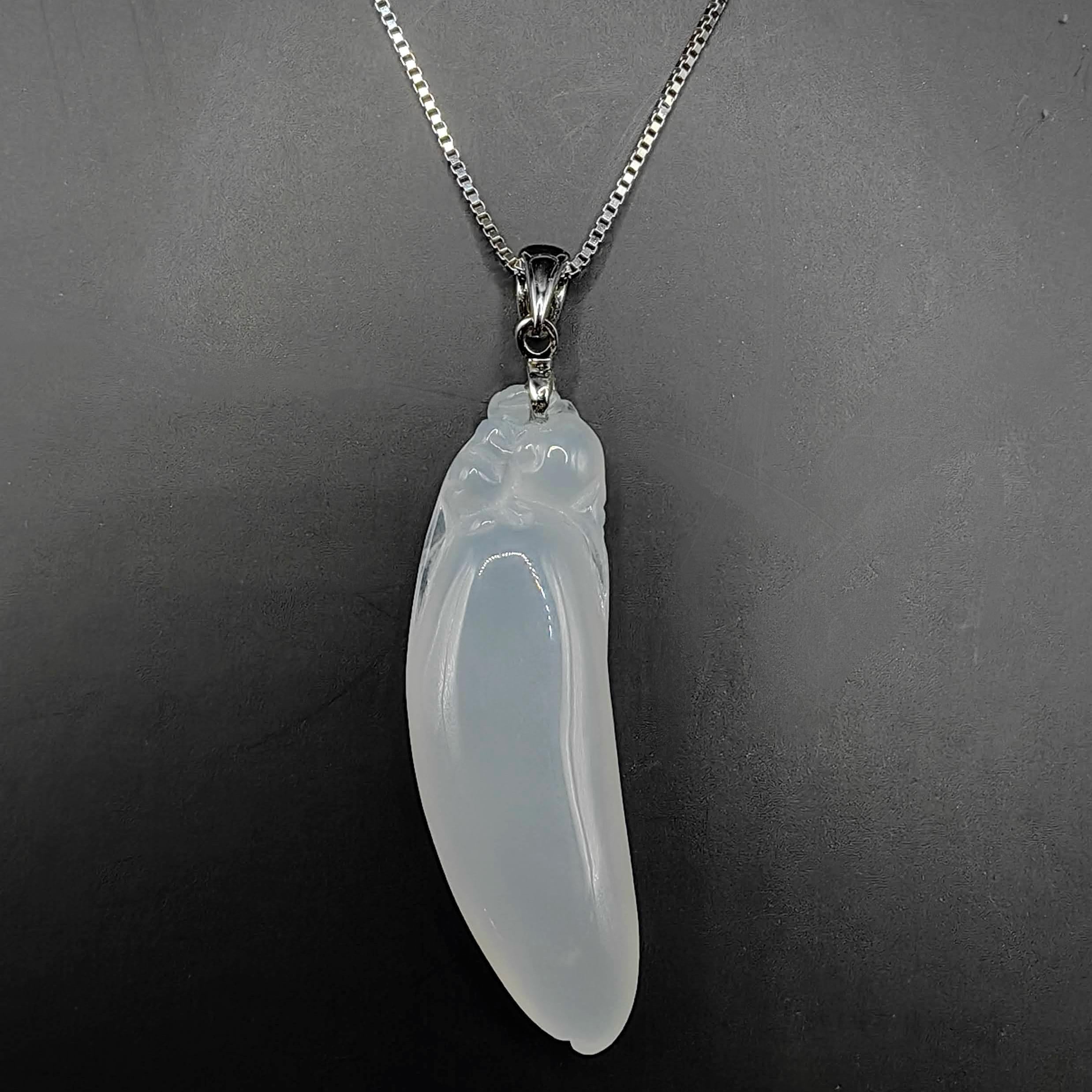 Entdecken Sie die zeitlose Schönheit und die kraftvolle Symbolik unseres Glücksbohnen-Anhängers aus weißem burmesischem Jadeit, gefasst in luxuriösem 18-karätigem Weißgold. Dieser exquisite Anhänger zeigt ein sorgfältig von Hand geschnitztes