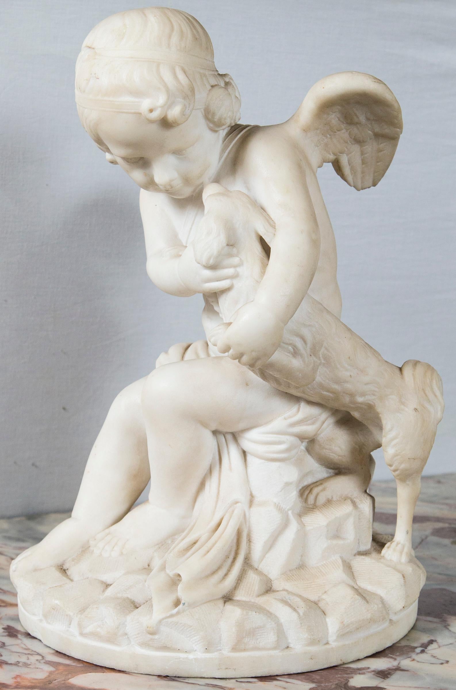 Cupid has his arm around his dog on his left side. He has a band around his head, wears a drape across his lap. There is a quiver below his right wing. He sits on a rocky base. It is unsigned.