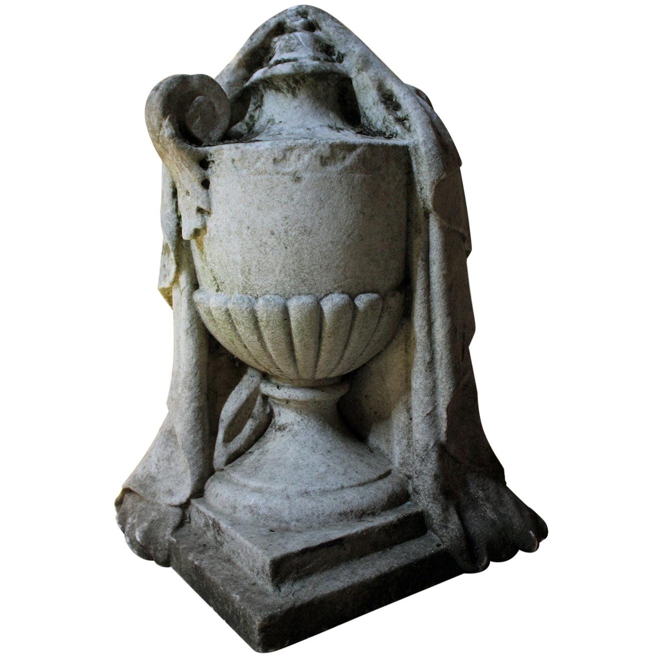 The fine and large and heavy solid white marble funerary monument carved in the round in the form of a classical urn carved with fluid flowing drapery, with one loop handle visible to a fluted conical body, to a square plinth base, the whole