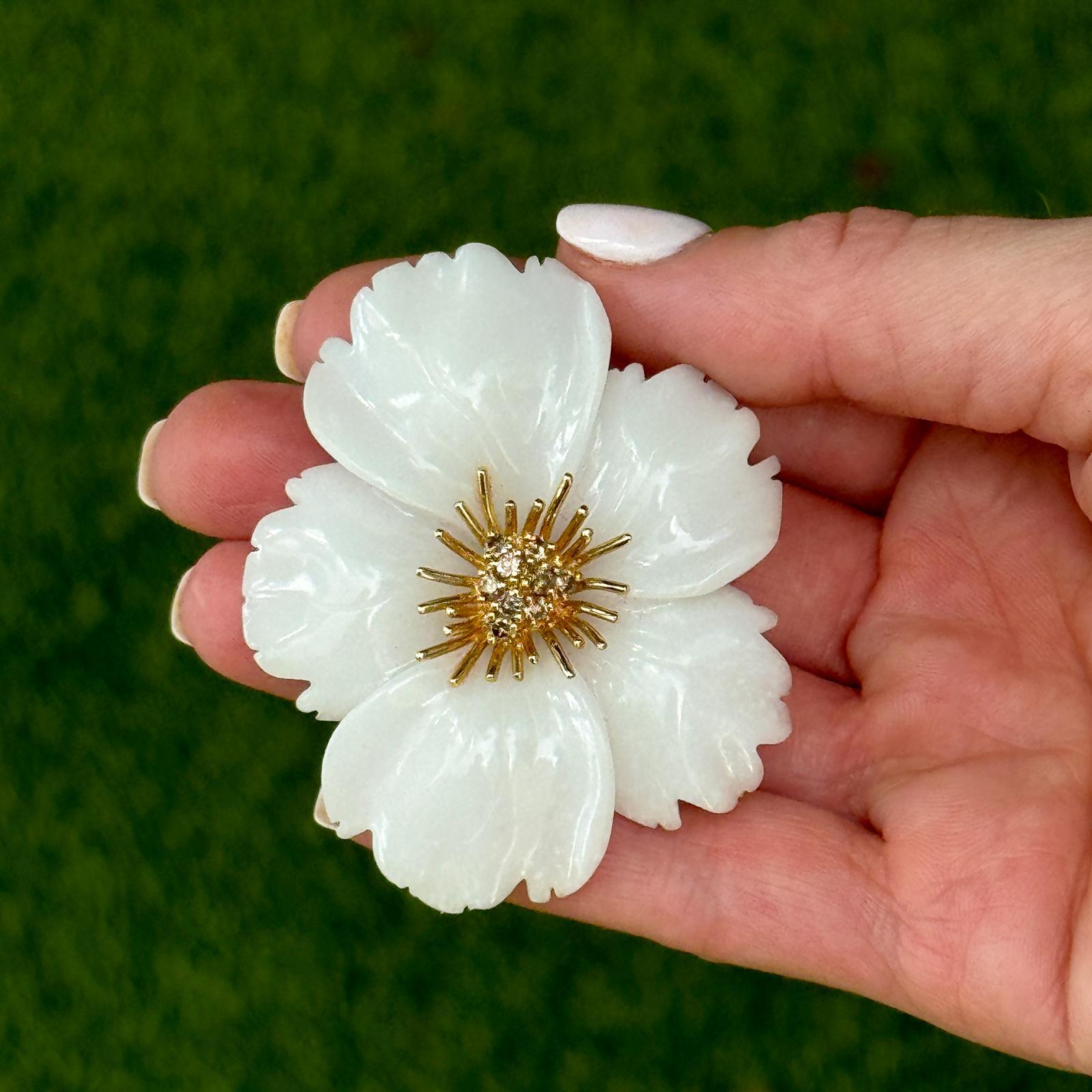 The Hand-Carved White Jade and Diamond Brooch is a stunning example of intricate craftsmanship and timeless elegance. This exquisite brooch features a beautifully hand-carved white nephrite jade flower, highlighted by  9 round brilliant sparkling