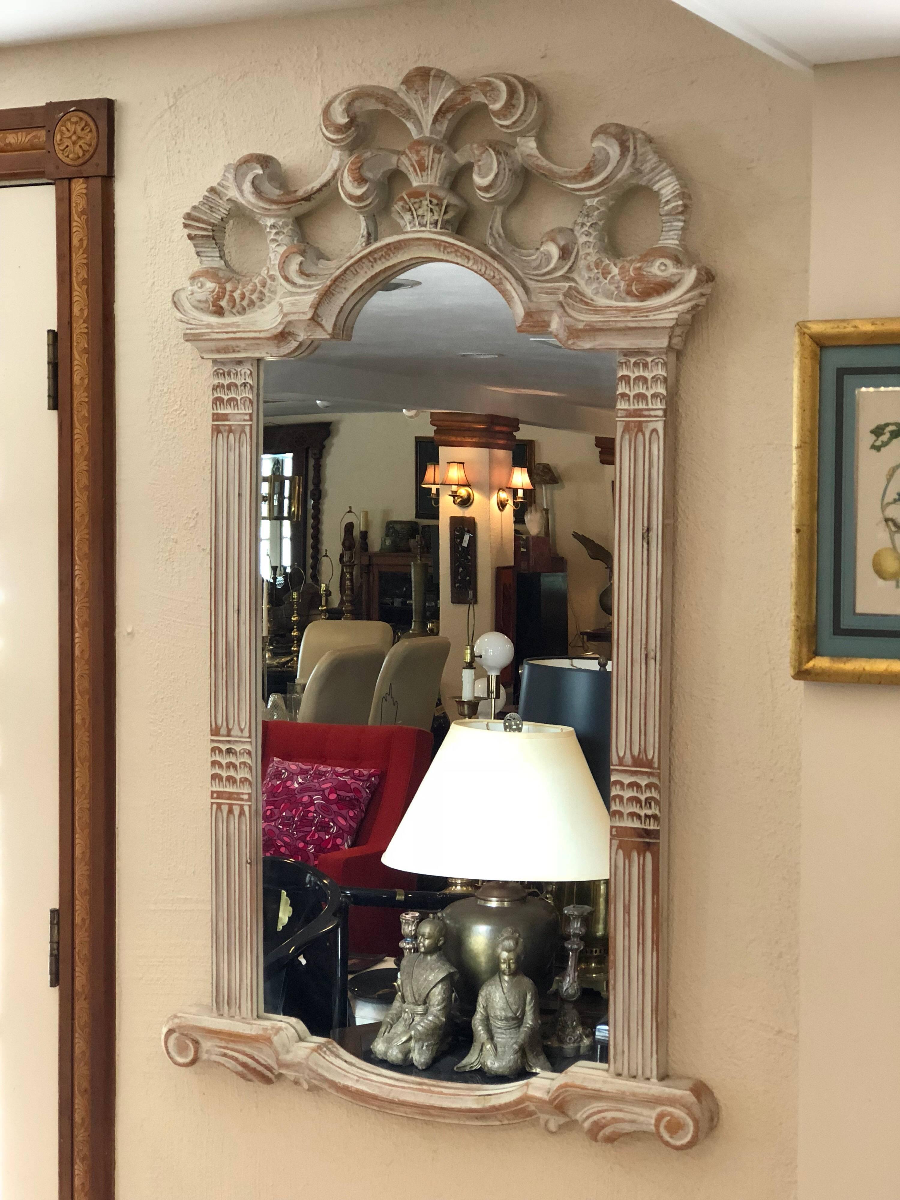 Carved white-washed wooden mirror from Spain. Beautiful details of carved wooden dolphins make up this mirror. This unique and unusual mirror would look great in an entry way, bathroom or above a small chest of drawers or an upright bar cart. This