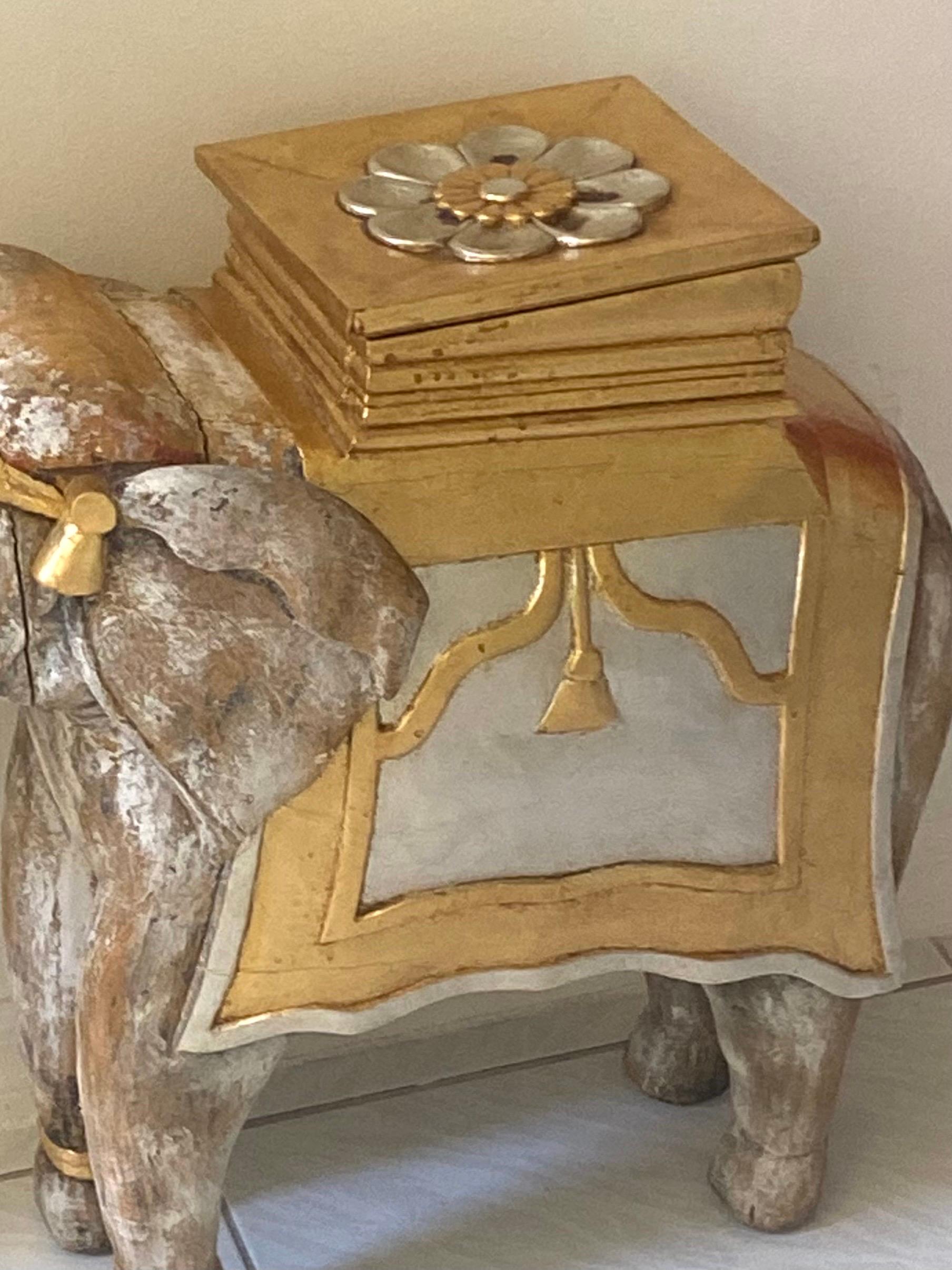 A very charming hand carved pickled wood elephant in full gold and silver leaf attire. The seat is a lid which can be removed to reveal a nice hidden storage area. This piece is versatile and can be used as a sculpture, side table, garden