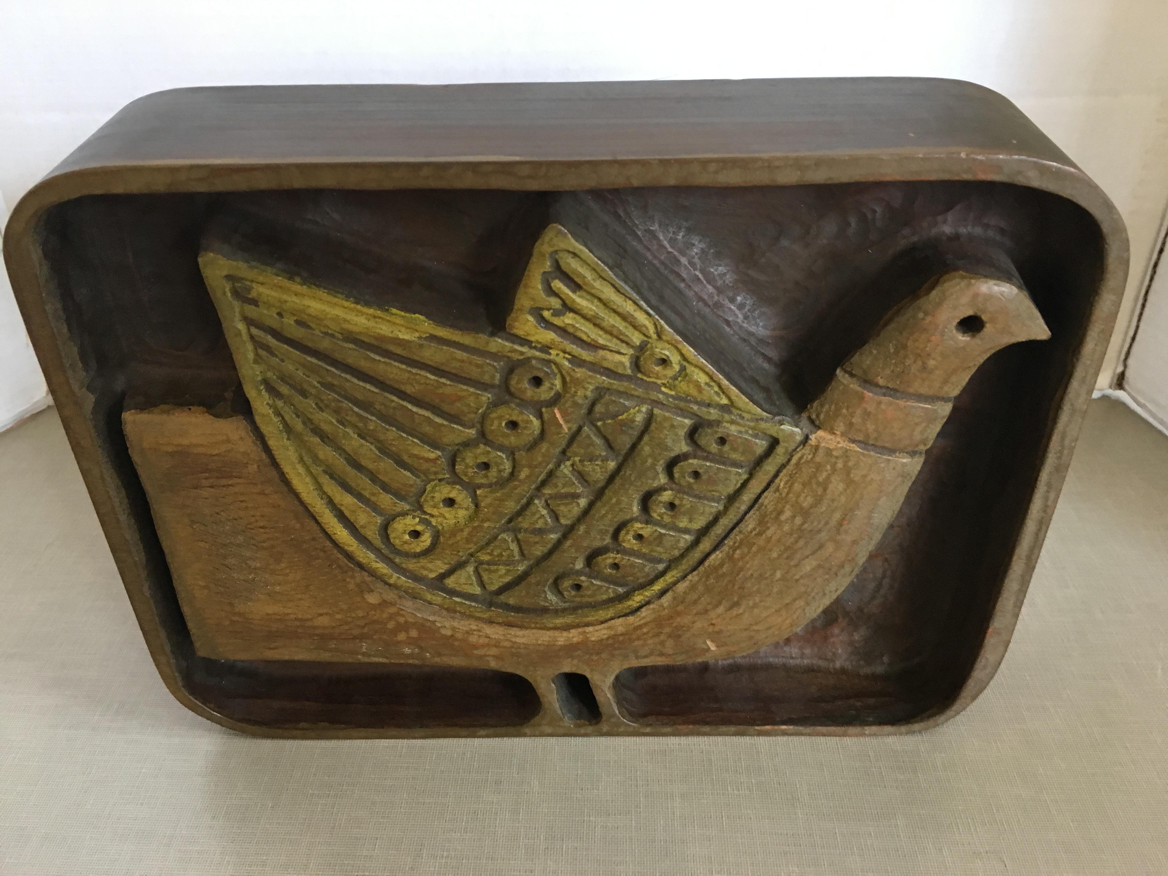 A carved wood bird plaque by Evelyn Ackerman.