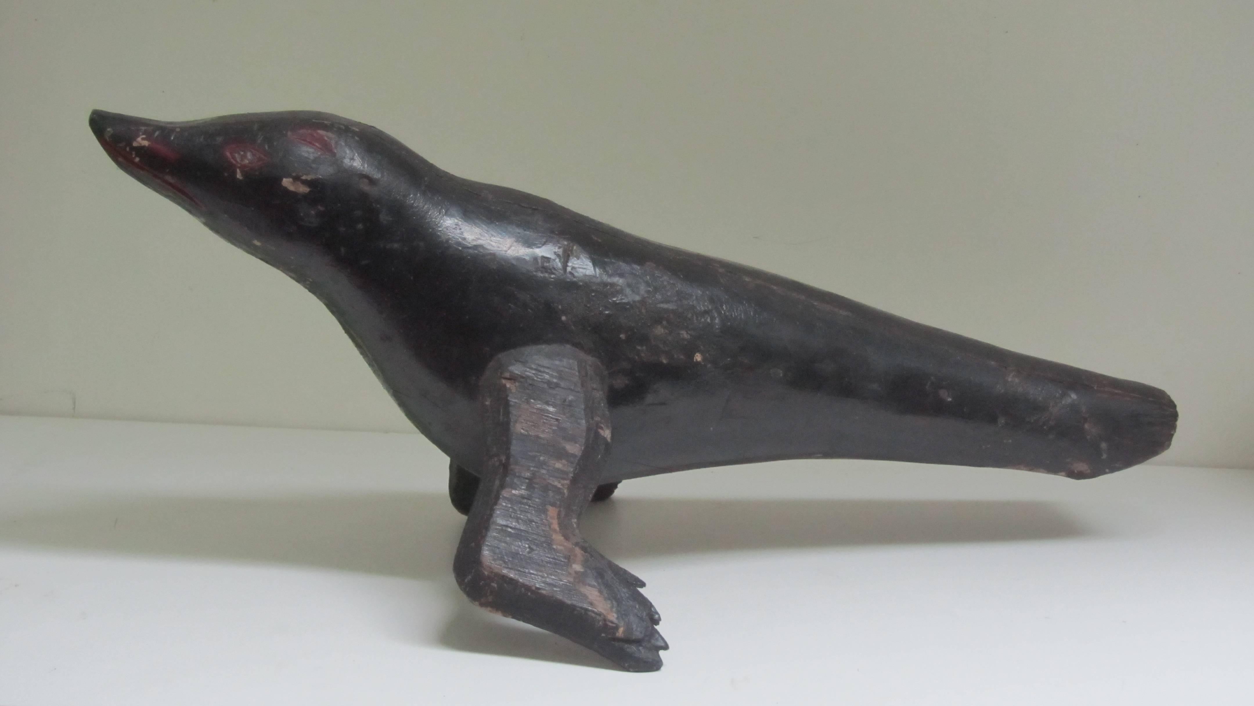 Painted wood seal of carved and pieced wood. The seal is of stylized form with a pair of fins. Red markings to the head. Mounted over a black metal base.