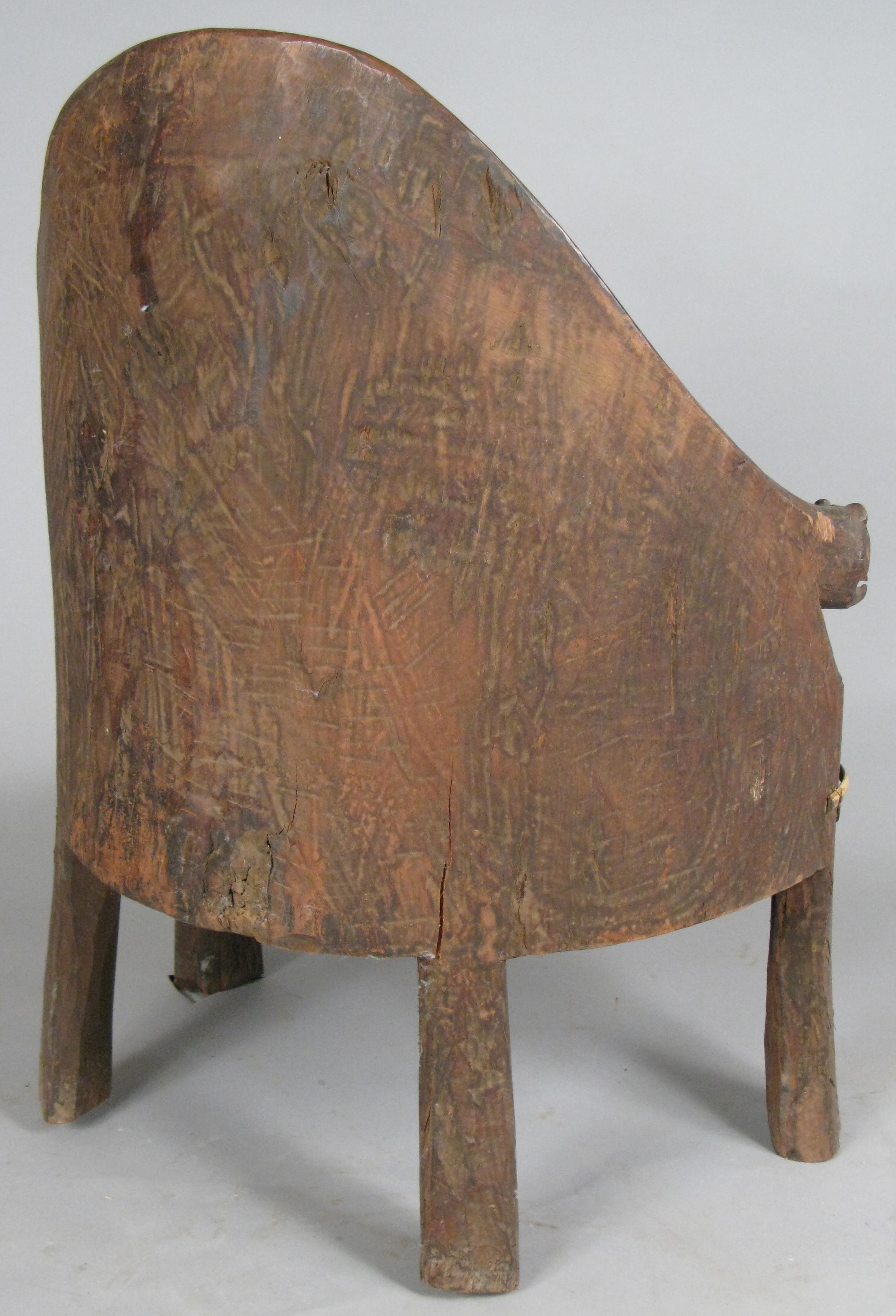 An outstanding chief's chair from Nagaland in northeast India. This chair, carved from a single piece of wood, has a curved back and is detailed with carved motifs around the seat, carved heads at the ends of the arms, and is decorated with