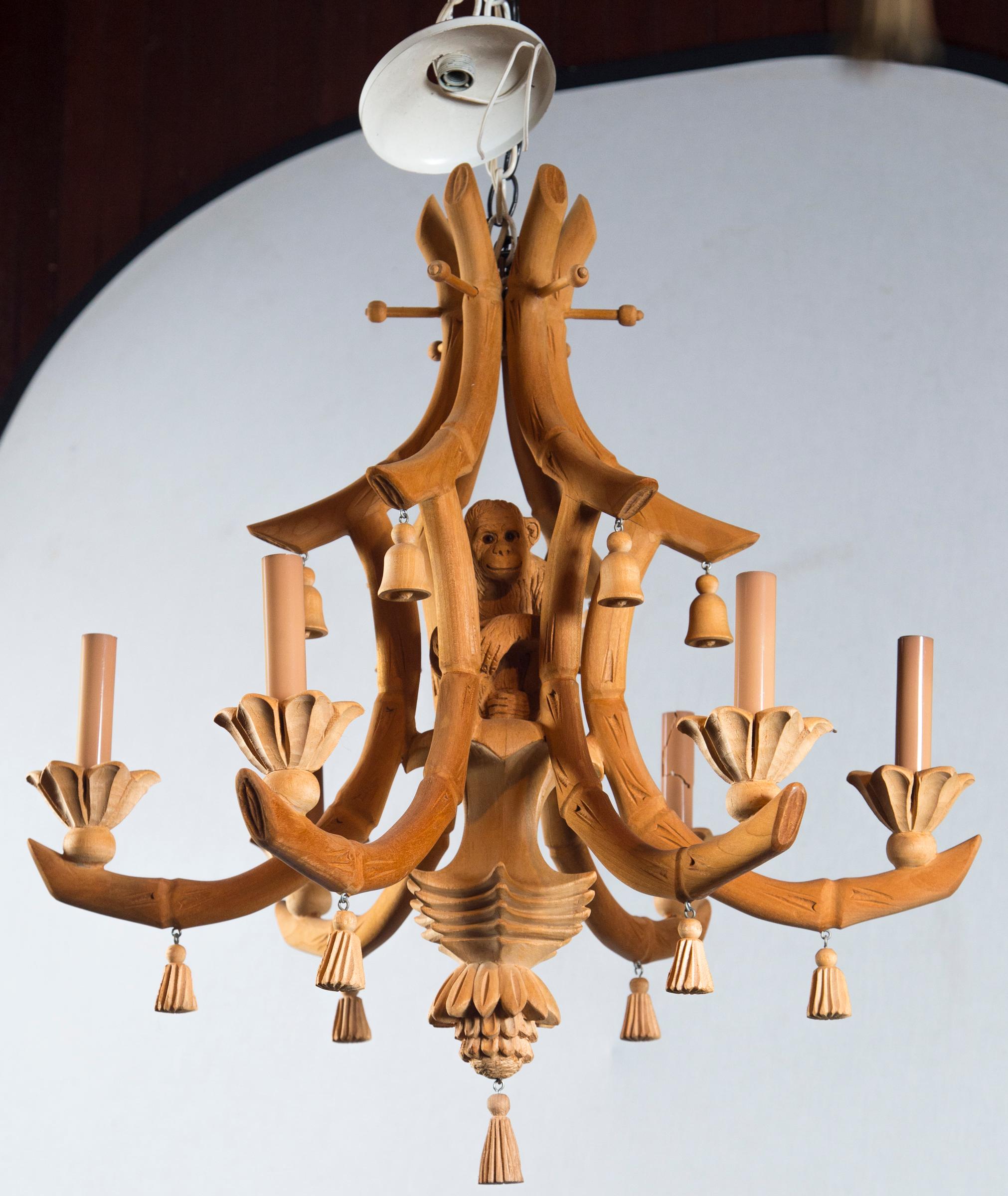 Unusual carved wood chinoiserie monkey chandelier with carved wood tassels. Six arms for chandelier bulbs. It is nicely detailed with tassels, bells and unique carvings.