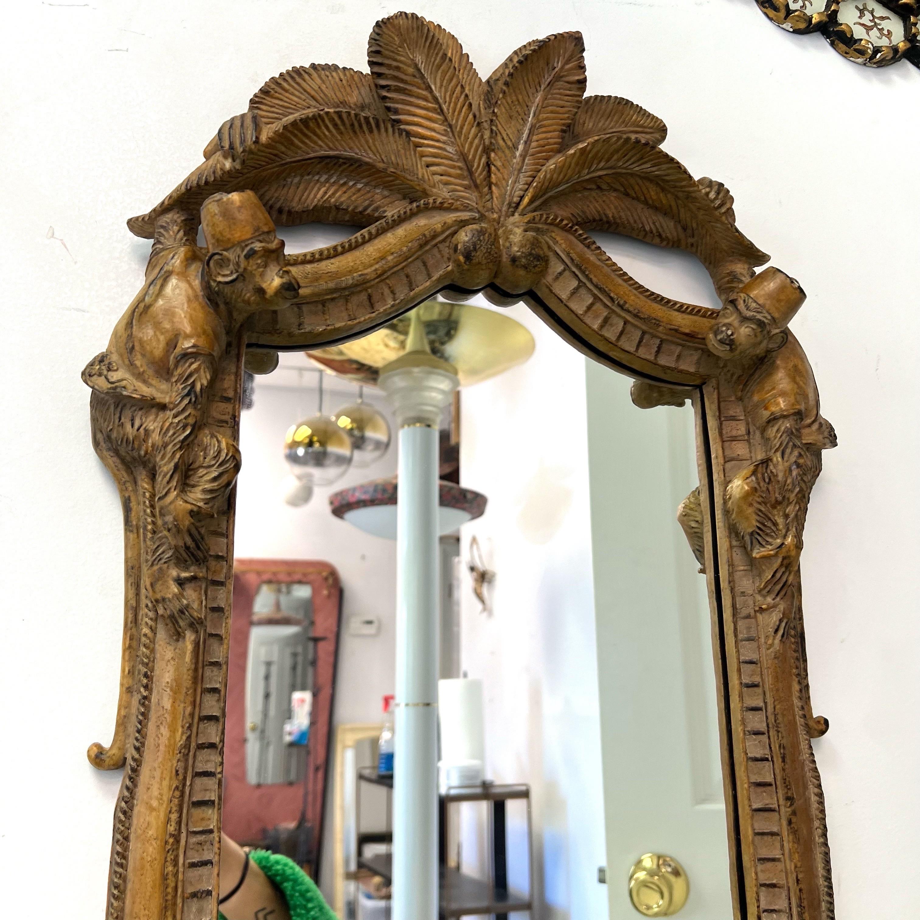 Whimsical Palm fronds adorn the top of the mirror  and each palm tree trunk flanking the mirror have a monkey hanging on.  Very Palm Beach Chic.  Bill Huebbe Style