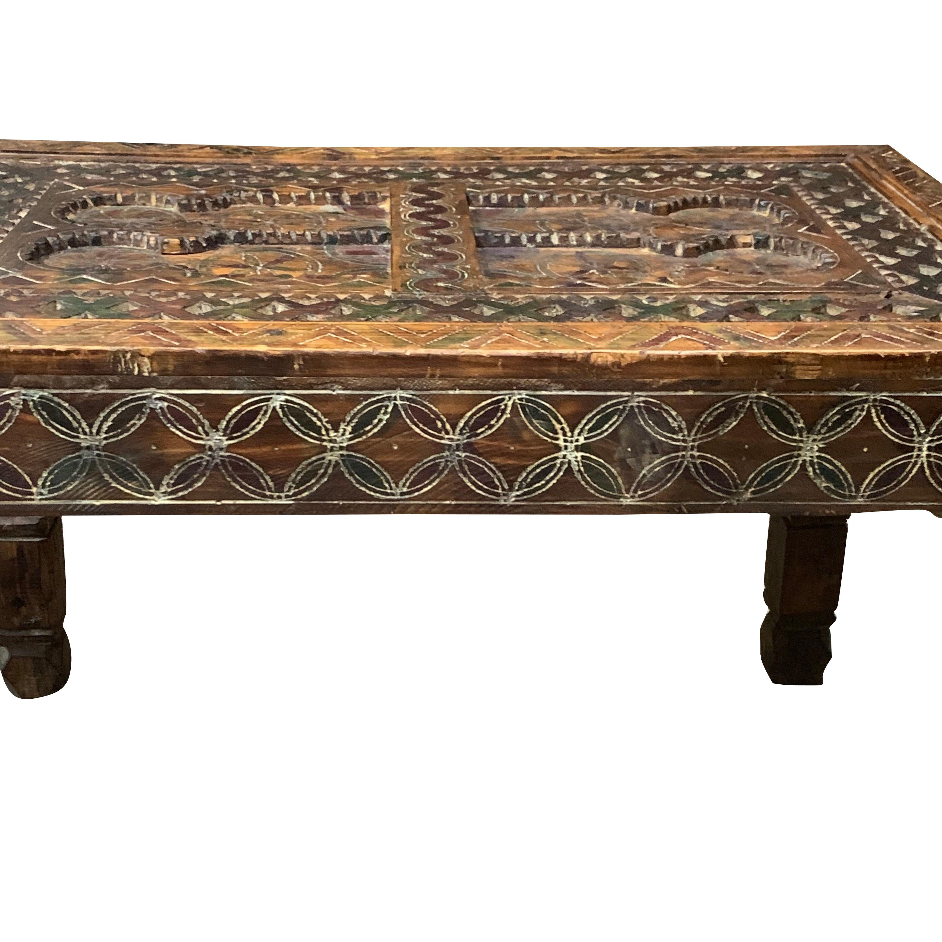 19th century rectangular coffee table from the Sahara region of Morocco.
Multicolored decorative cedar wood carved top with carved border and chevron patterned legs.
The glass top protects the detailed carvings on the top.
