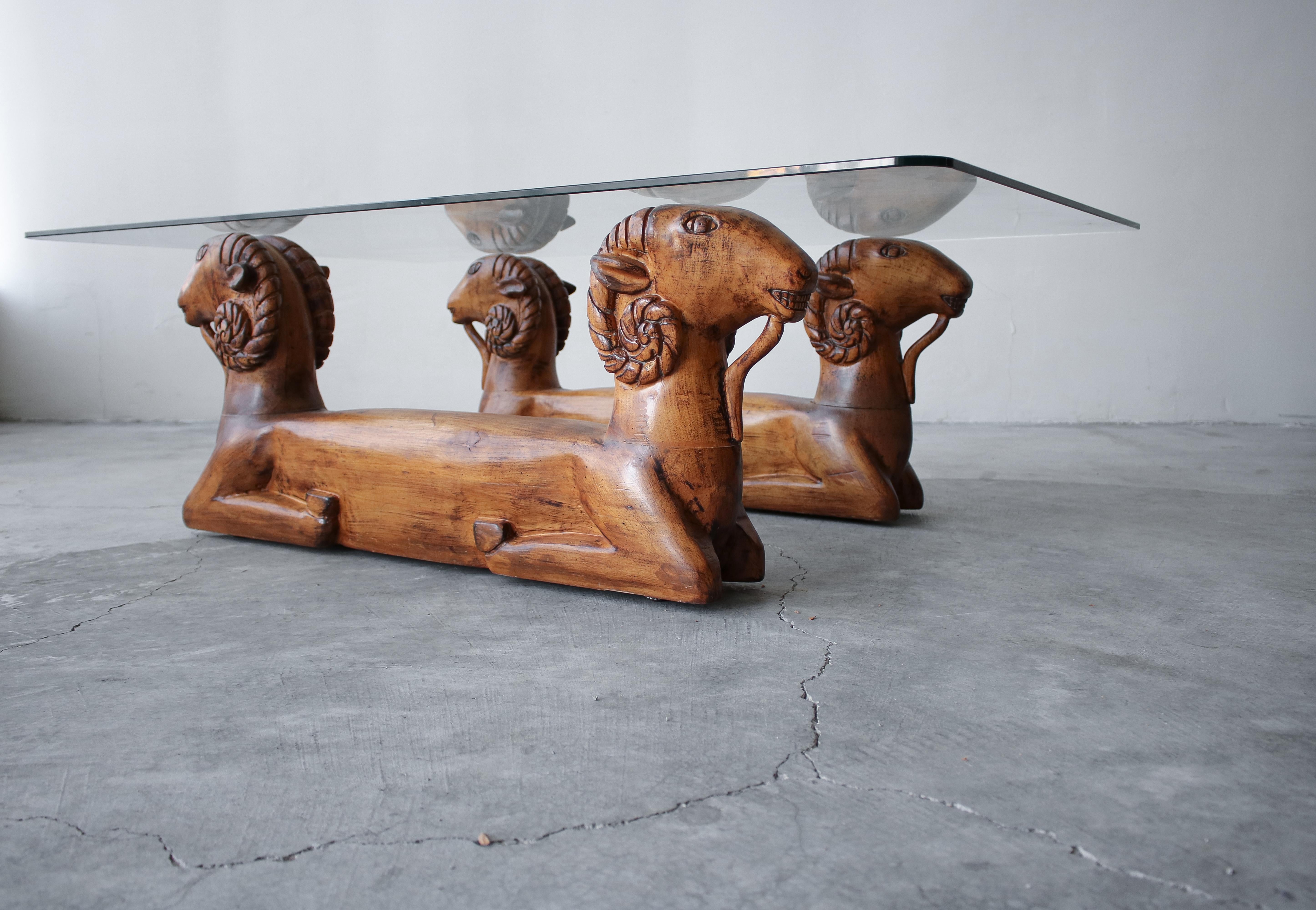 Unique vintage pair of carved wood, double rams heads make up this chic coffee table. The bases can support a larger piece of glass.

Bases are in goods condition. They show patina to the wood from age and use, but no damage. She pictures for