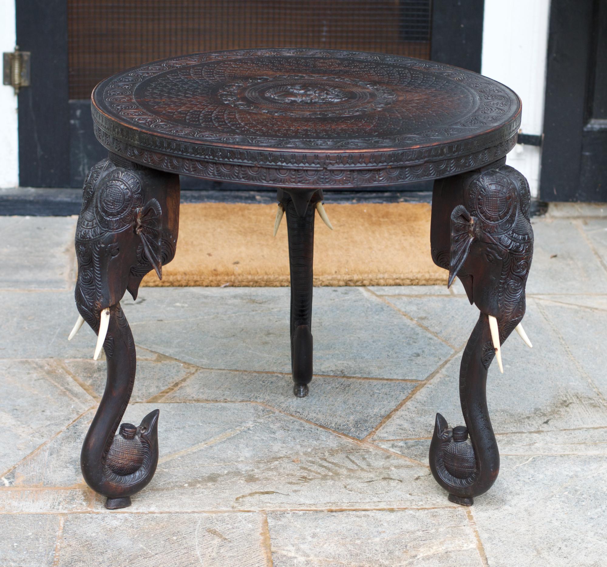 Intricately carved side table having elephant formed legs and a fantastically detailed top. The Asian-Indian produced round end table will supply a stylish and global look wherever one chooses to employ it. Sturdy throughout. Lots of breaks and