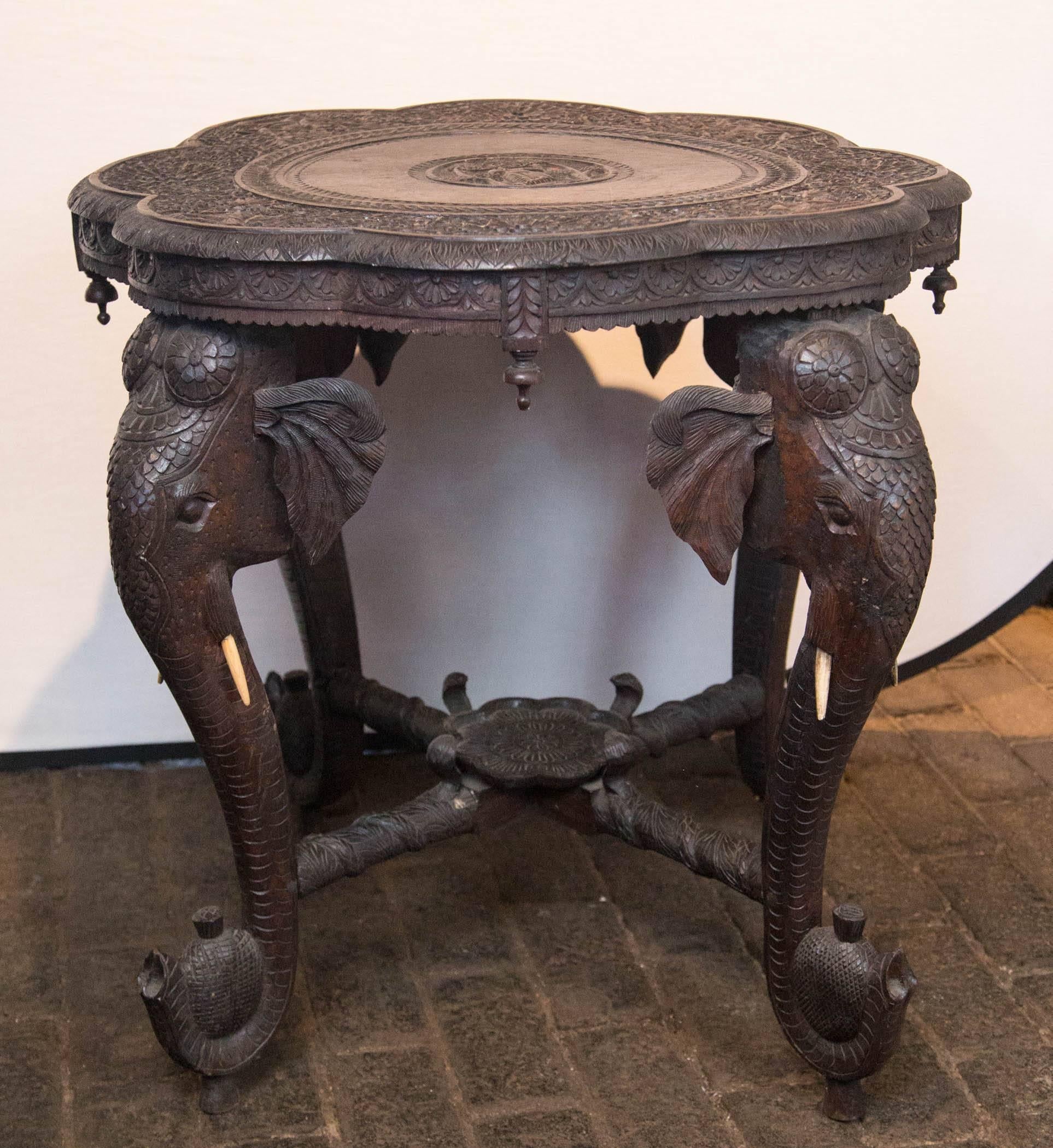 Anglo Raj round carved wood table with elephant heads and tusks.
Tabletop: 30 inch diameter. Cracks with age but sturdy.