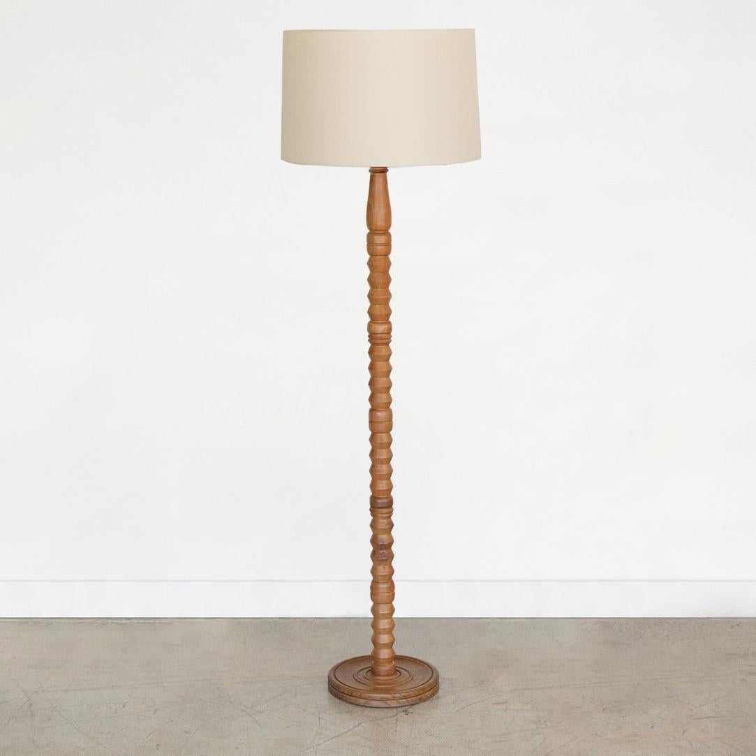 Beautiful carved wood floor lamp in the style of Charles Dudouyt from France, 1940's. Original light wood finish in great vintage condition. Newly re-wired and new linen shade. Takes one E26 base bulb, 60 W or higher using LED.