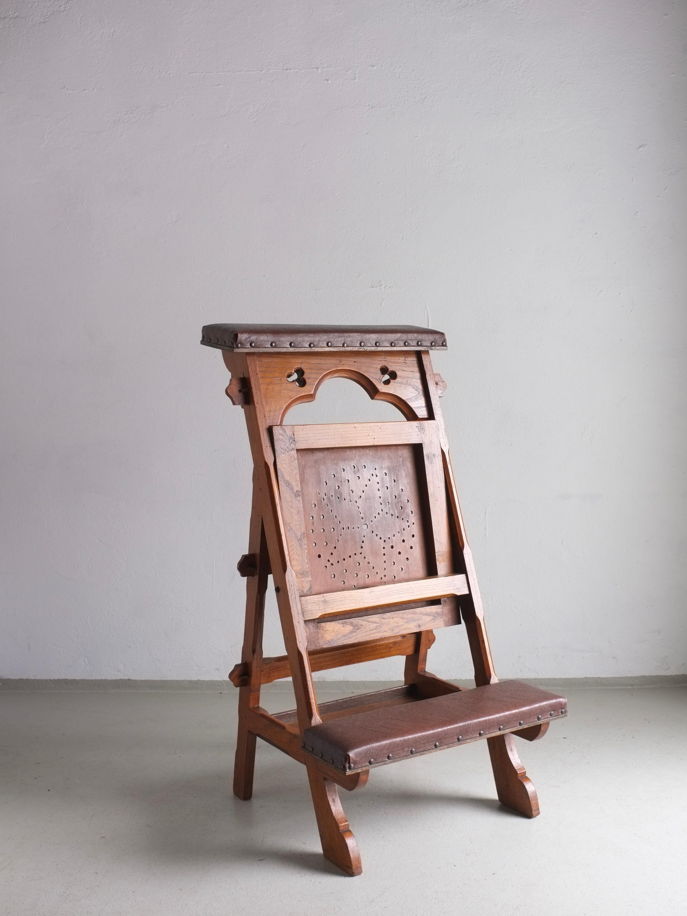 Carved wood prayer chair with a folding seat, upholstered with faux leather.