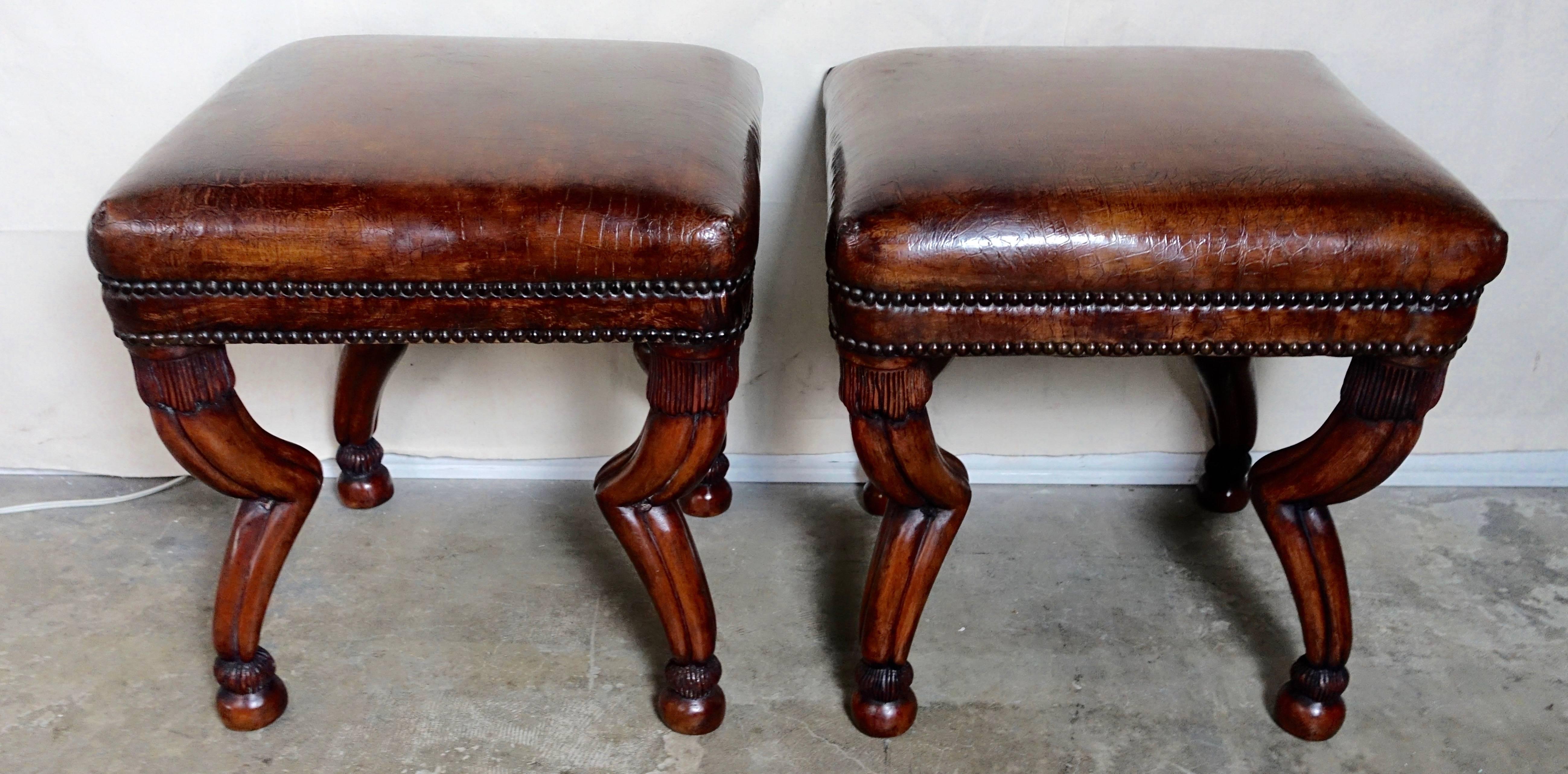 Pair of custom tobacco colored benches made with four hand-carved gazelle style legs upholstered with leather that is embossed with a crocodile pattern. The benches are finished with two rows of nailheads.