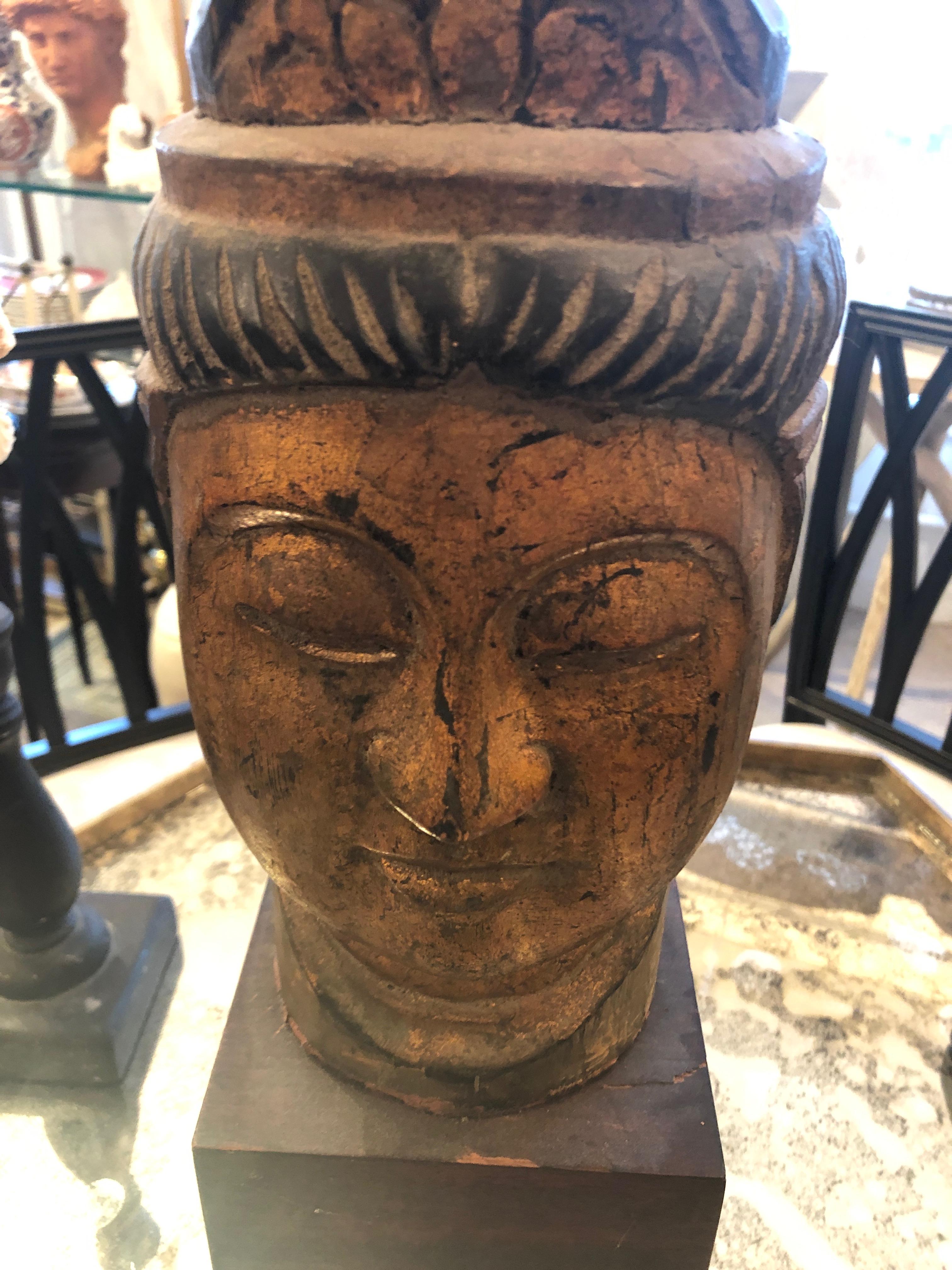 A handsome decorative Asian bust having carved and gilded wood serene face with tall headdress. Rests on ebonized chunky wooden base.