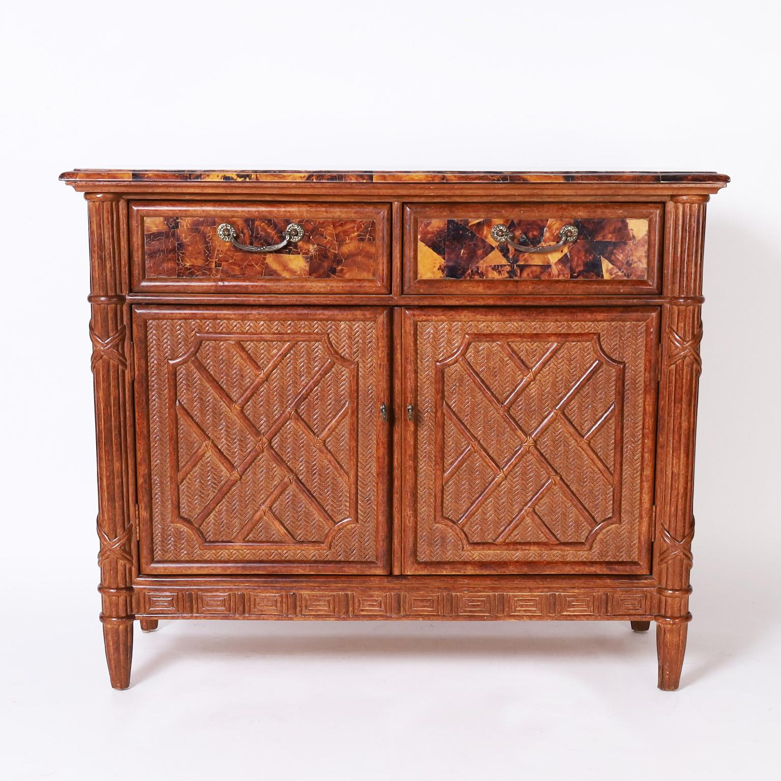 Dynamic mid century cabinet with a pen shell mosaic beveled top over a case with two pen shell covered drawers, two grasscloth doors with Chinese chippendale bamboo applied decorations, grasscloth sides, greek key carved skirt and beaded tapered
