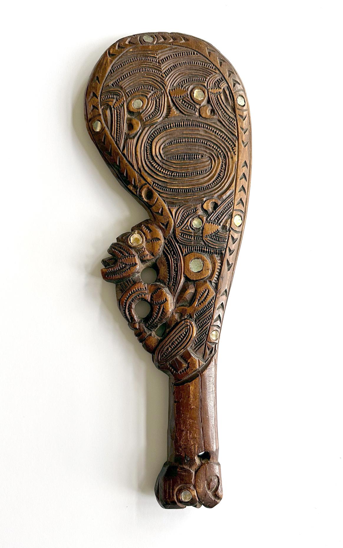 A wood club known as Wahaika intricately carved and inlayed with small round shells from New Zealand circa 1920s. The hand-hold club was traditionally used as a close-range combat weapon before the European contact by Māori people, indigenous