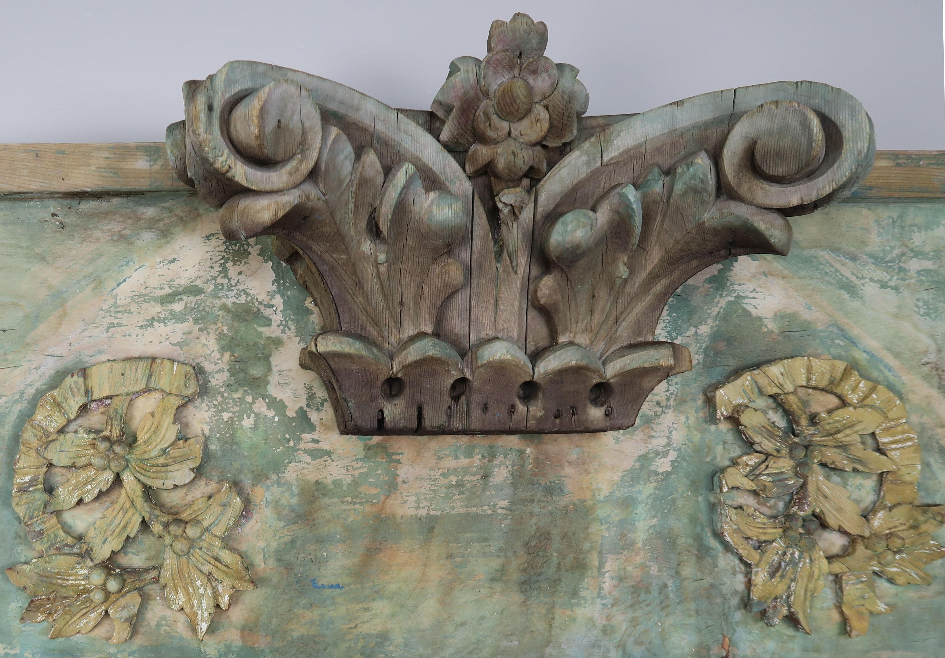 A carved wood painted green panel made of antique elements including a 19th century capital with carved acanthus leaves and carvings.