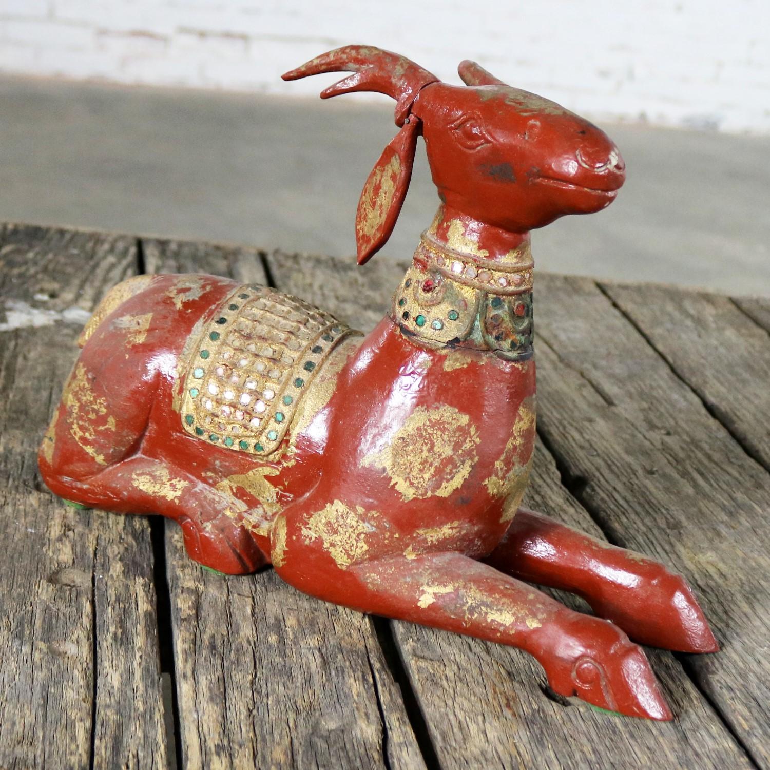 Beautiful carved wood recumbent deer from Thailand. Lacquered with a Chinese red or terracotta color and decorated with glass jewels, mirror, and gilding. It is in wonderful vintage condition, circa 20th century.

This carved wood recumbent deer