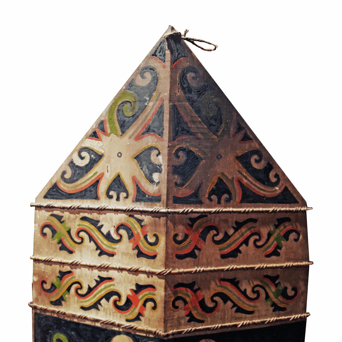 A polychromed, hand-carved shield, circa 1940, from the region of Indonesian Kalimantan in the island of Borneo. Mounted on a black metal stand. 

Dimensions: Shield alone: 53