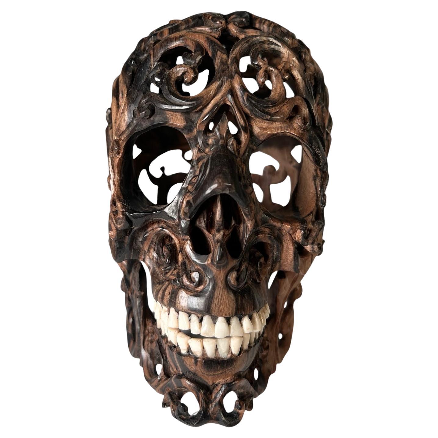 Scultura asiatica di teschio in legno intagliato con denti autentici e mascella mobile. Fine del XX secolo.