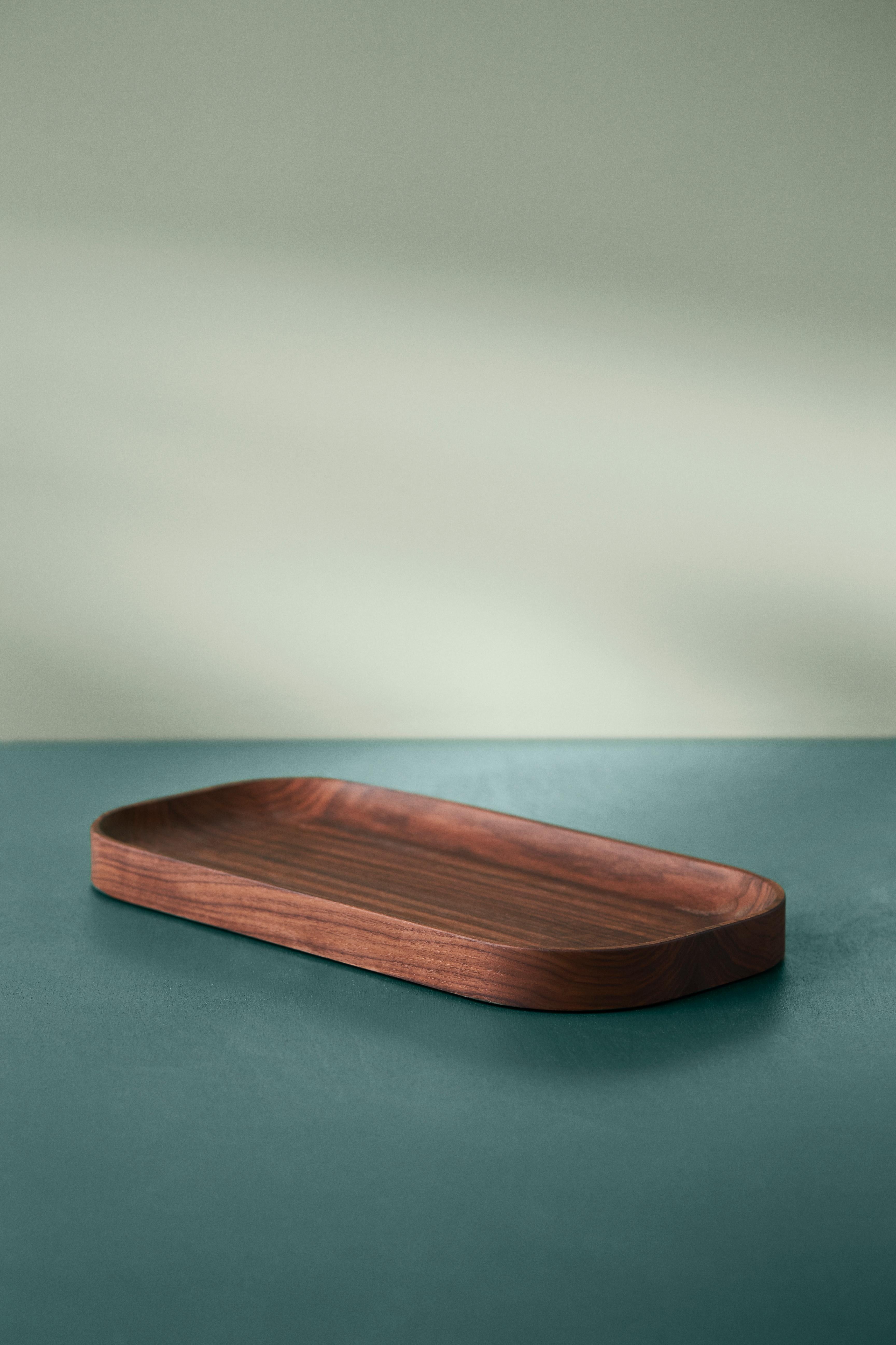 Exquisite wooden trays with an organic design and understated elegance. The carved wood trays are made of solid wood, exuding an exclusivity that makes them a beautiful bed for fruit, vegetables and nuts, an elegant design element in a still life