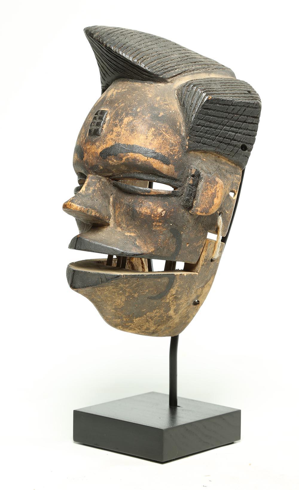 Holzgeschnitzte Ogoni-Stammesmaske mit beweglichem Kiefer, modisches Haar, Nigeria, frühes 20. Jahrhundert.
Einige verbliebene Schilfzähne. Schwarze stilvolle asymmetrische Frisur und ausdrucksstarkes Gesicht. Auf speziellem Holz- und Metallsockel.