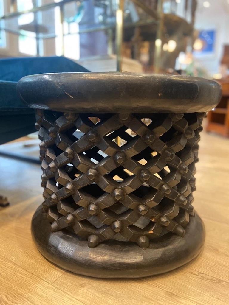 A hand carved vintage Bamileke African stool. 

With ornate carvings and a criss-cross detailed design, it is a perfect decorative piece as well as use as an occasional table or stool. 
