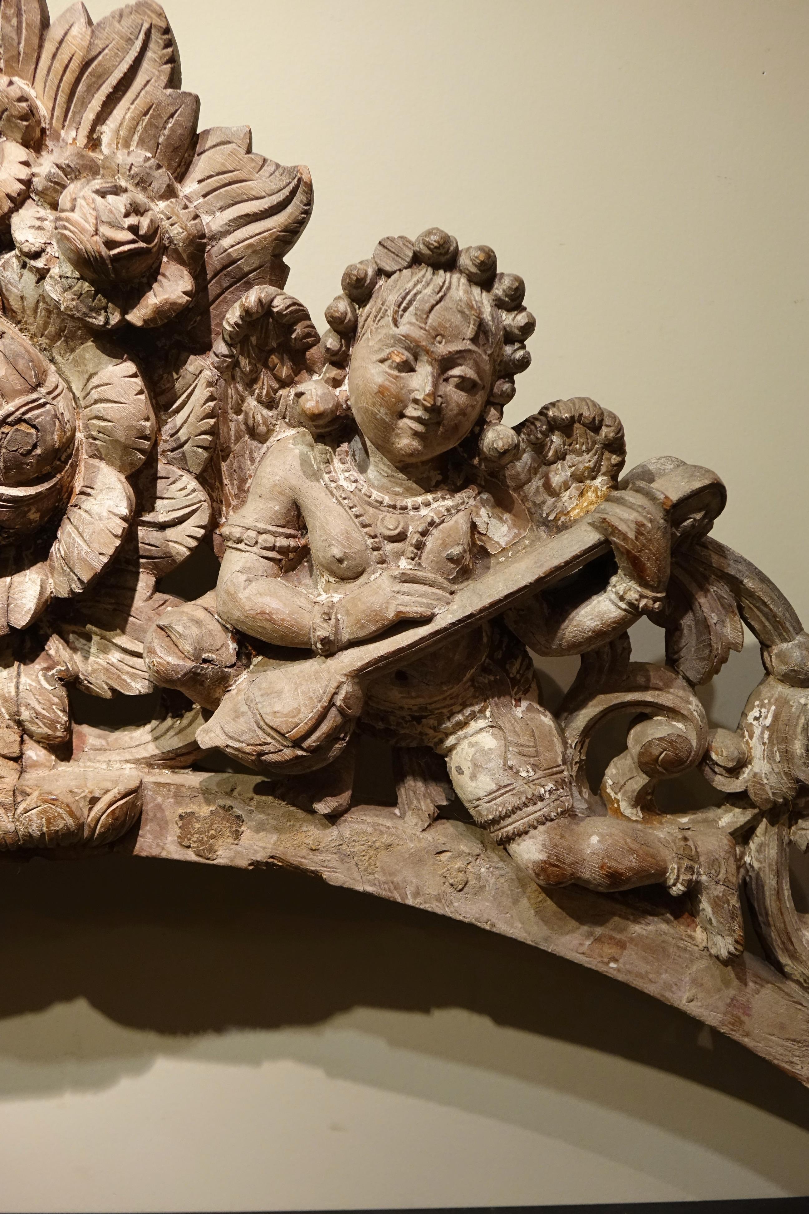 Rare carved wooden arch, formerly painted, with two musician angels in a floral decor.
Probably from a Christian shrine in Tamil Nadu, South India.
18th or 19th c.
91x57 
 In the colonial age many Portuguese, Dutch, British and Italian Christians