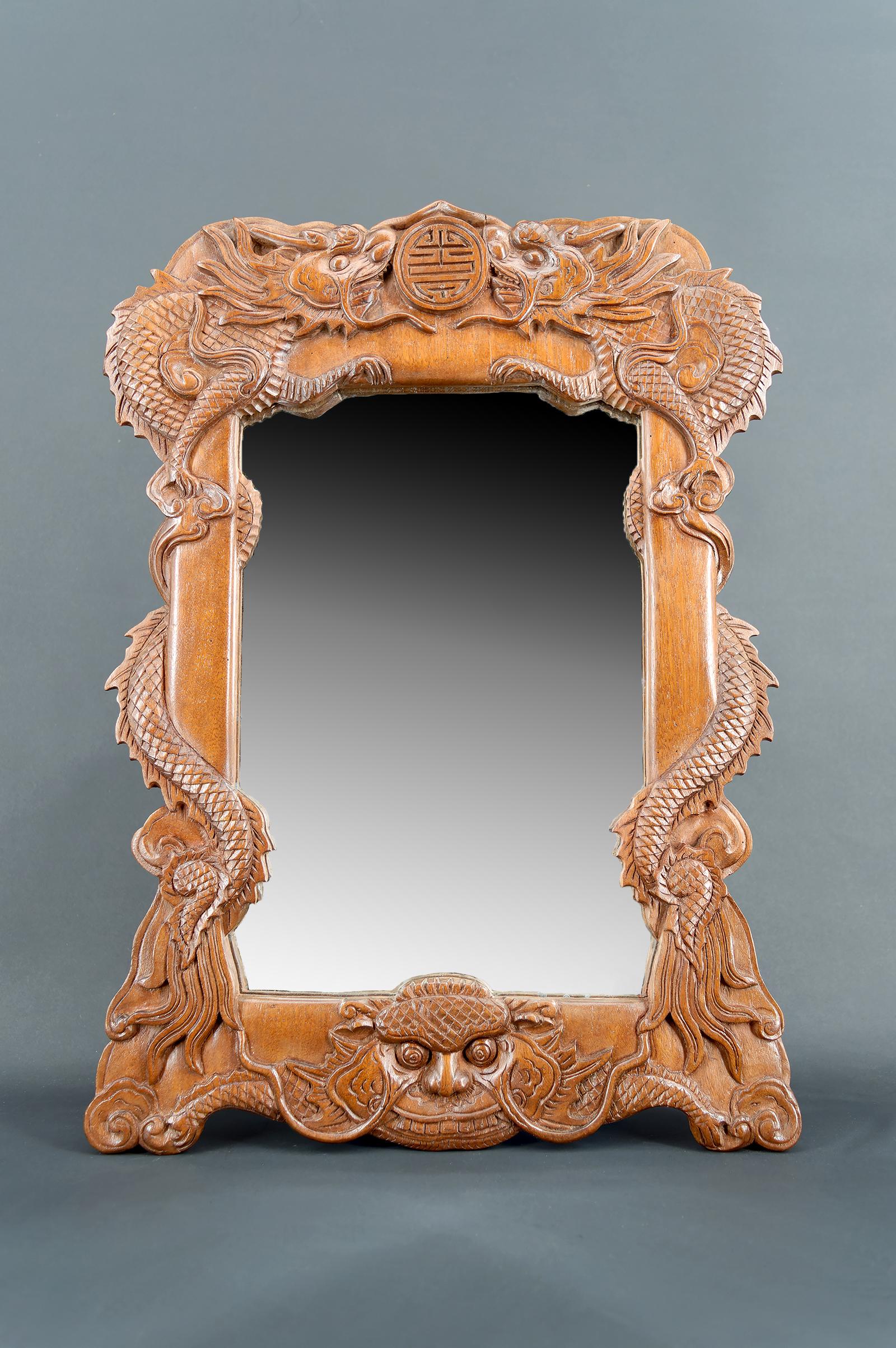 Miroir dragon en bois sculpté, Indochine, Circa 1900

Le cadre, exécuté avec un savoir-faire exceptionnel, présente une composition symétrique et dynamique : deux dragons majestueux, finement sculptés, émergent des coins inférieurs pour enlacer un