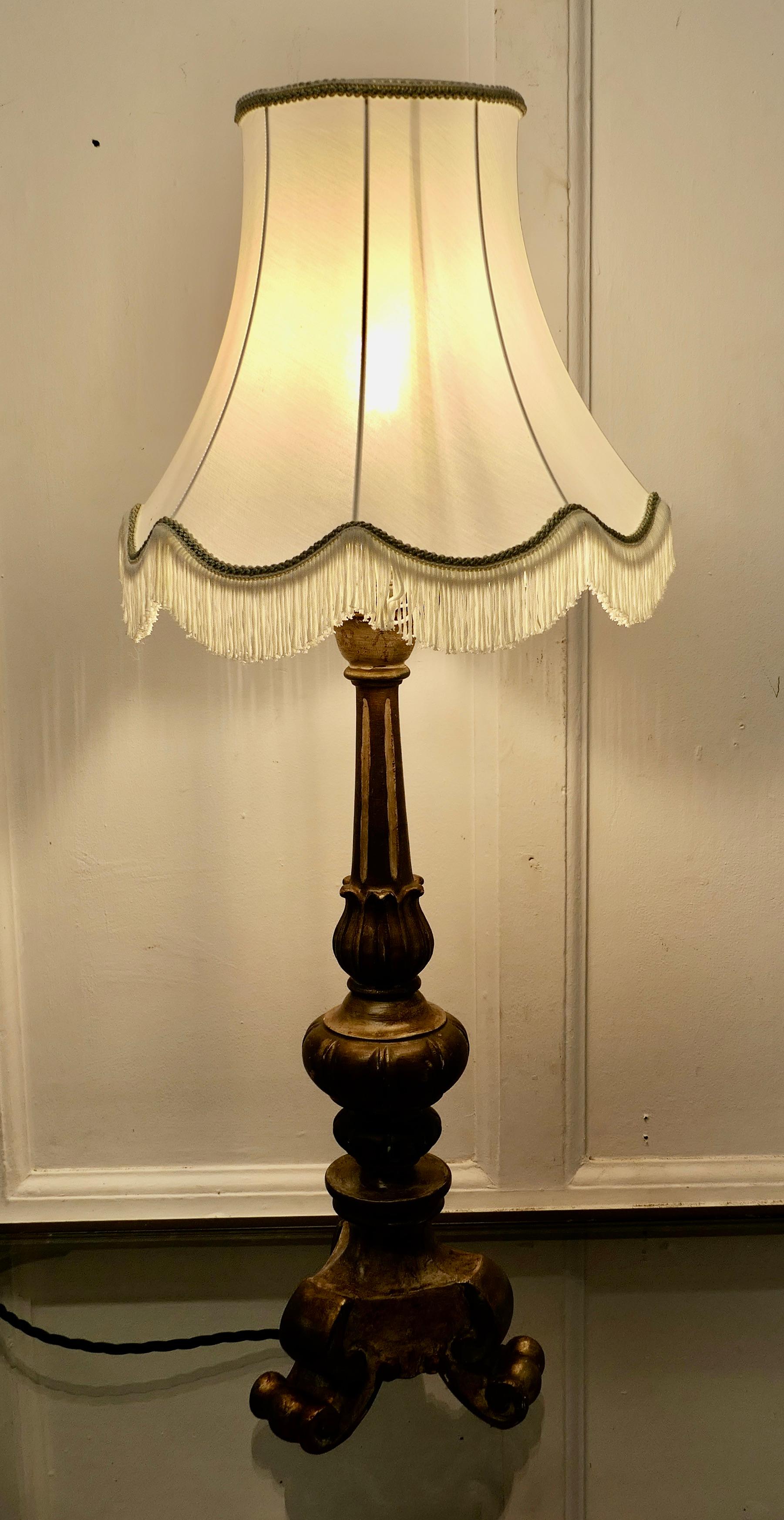 Carved Wooden Shabby Gilt Table Lamp

This is a great statement piece, it has a chunky carved base, the old paint has a distressed appearance it is mostly in an old gold and bronze finish
It comes with a beautifully tailored shade, the wiring is in
