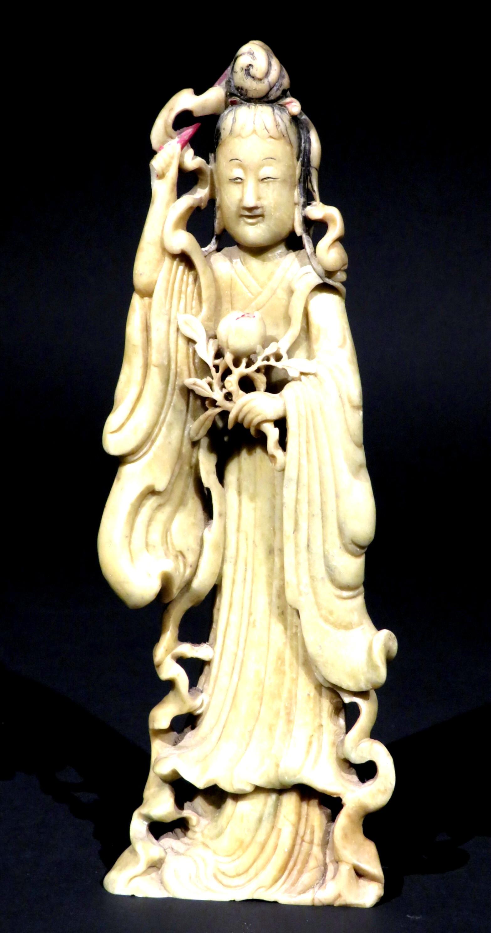 The finely carved full length figure of 'The Goddess of Compassion, Kindness & Mercy' shown attired in flowing robes, her hair in high chignon with her face effecting a serene and meditative expression with inked highlights, holding a lotus branch