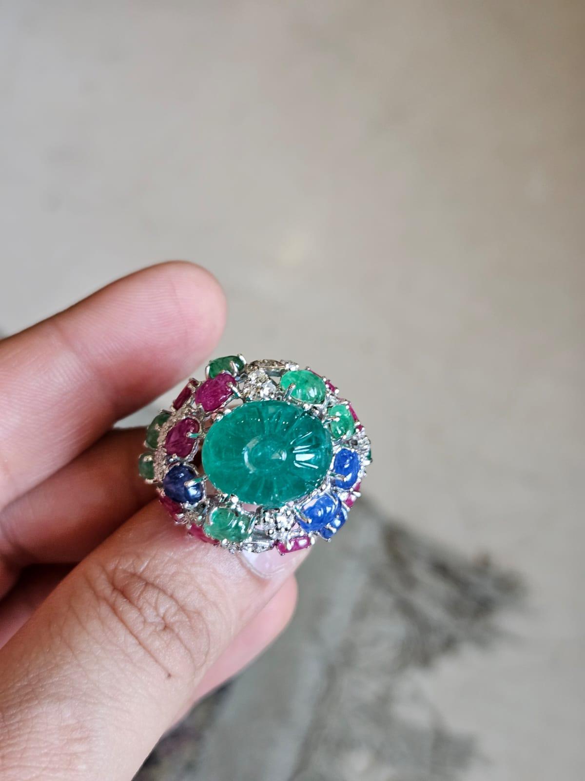 A very gorgeous and beautiful, Blue Sapphire, Emerald & Ruby Tutti Frutti Cocktail Ring set in 18K White Gold & Diamonds. The weight of the carved Emerald is 11.89 carats. The Emerald is completely natural, without any treatment and is of Zambian