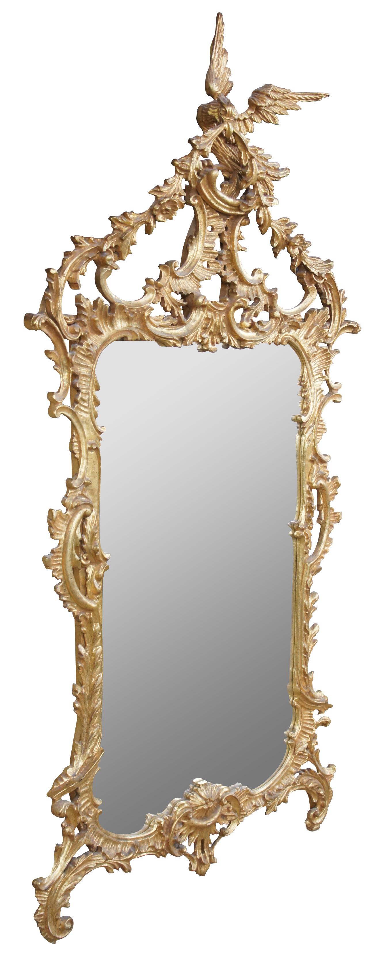 Vintage circa 1980s Baroque / Rococo / Chinese Chippendale inspired wall mirror by Carvers Guild. Made of wood, painted with antique gold leaf finish. Features ornate scalloped Italian design with florals, a wreath and dove or bird topper.
  